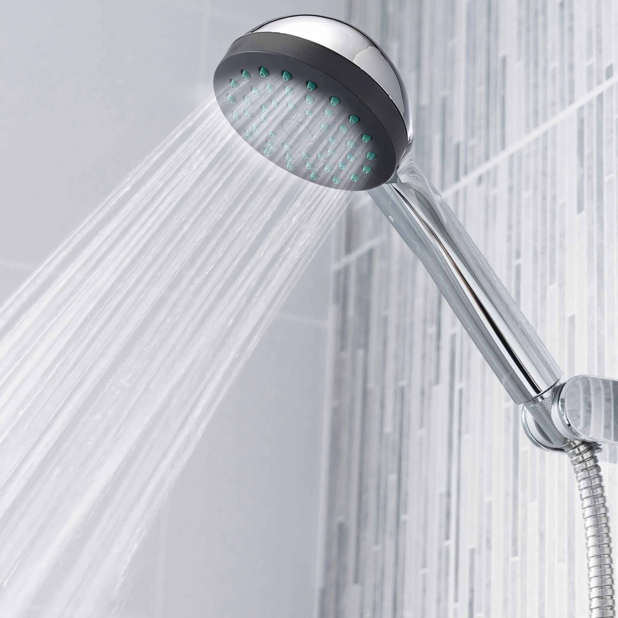 Eine Chromdusche sprüht Wasser gegen eine geflieste Wand.