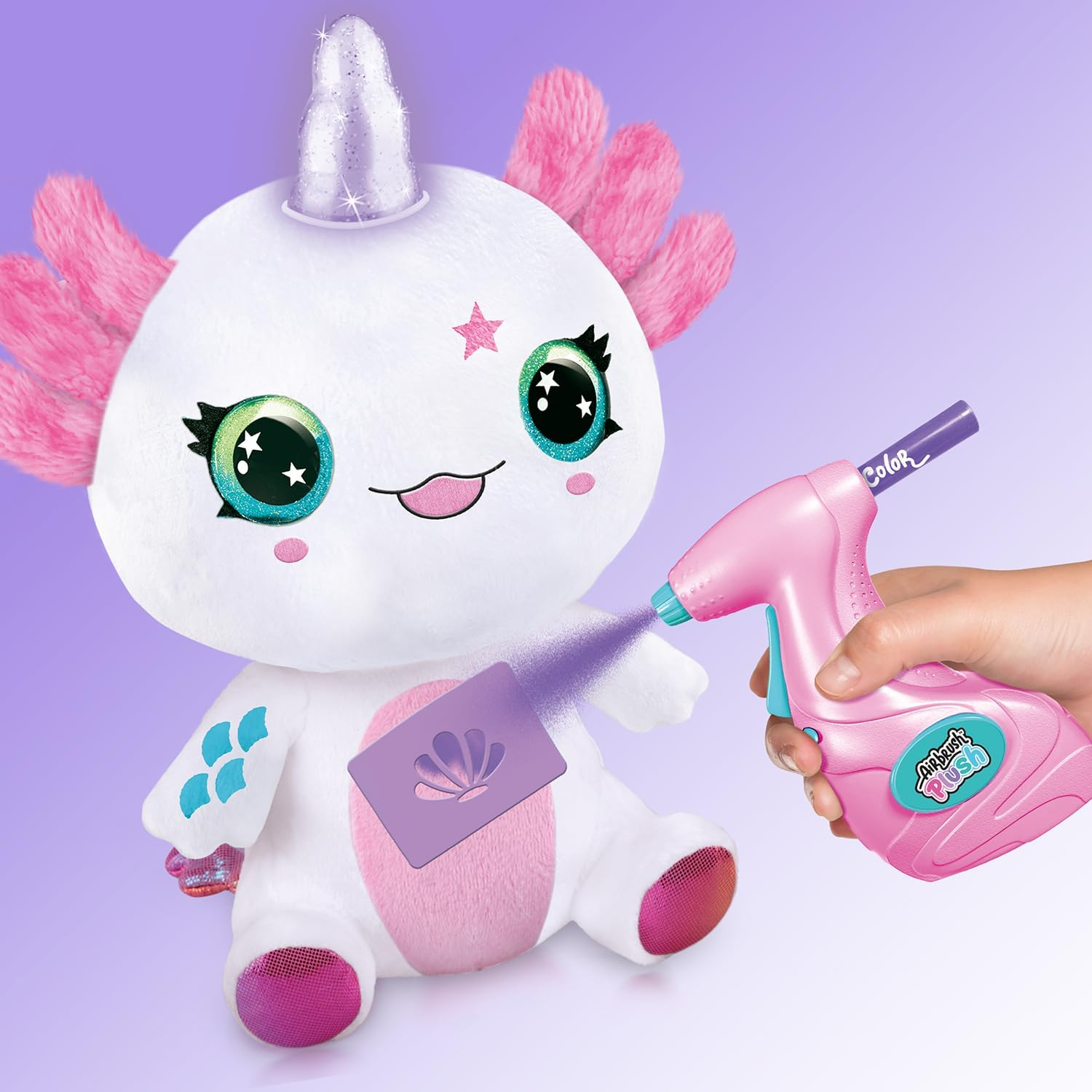 Un giocattolo axolotl di peluche bianco con corno da unicorno viene colorato di viola con uno strumento aerografo.