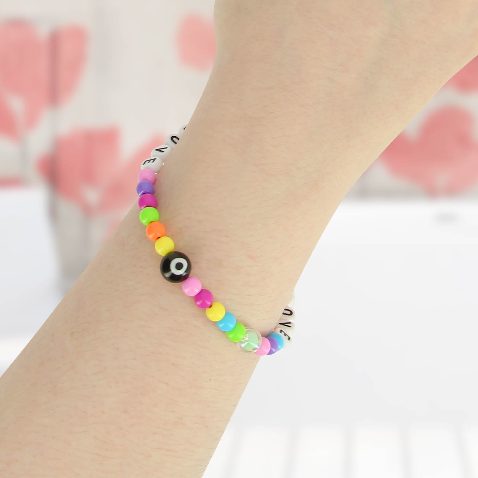 Un braccialetto colorato di perline con perline che compongono la parola 'LOVE' e un ciondolo occhio nero.