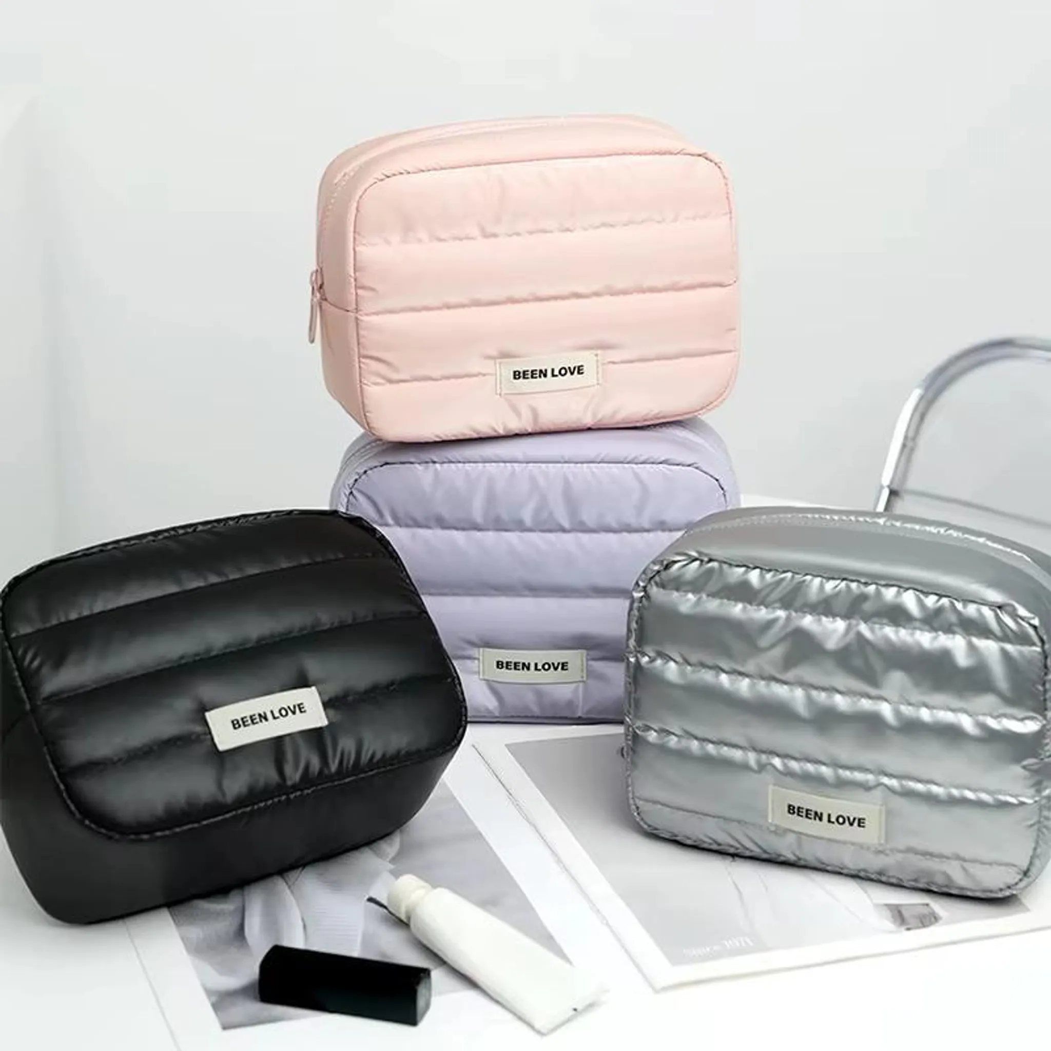 Drei gesteppte Kosmetiktaschen in Rosa, Lavendel und Silber.