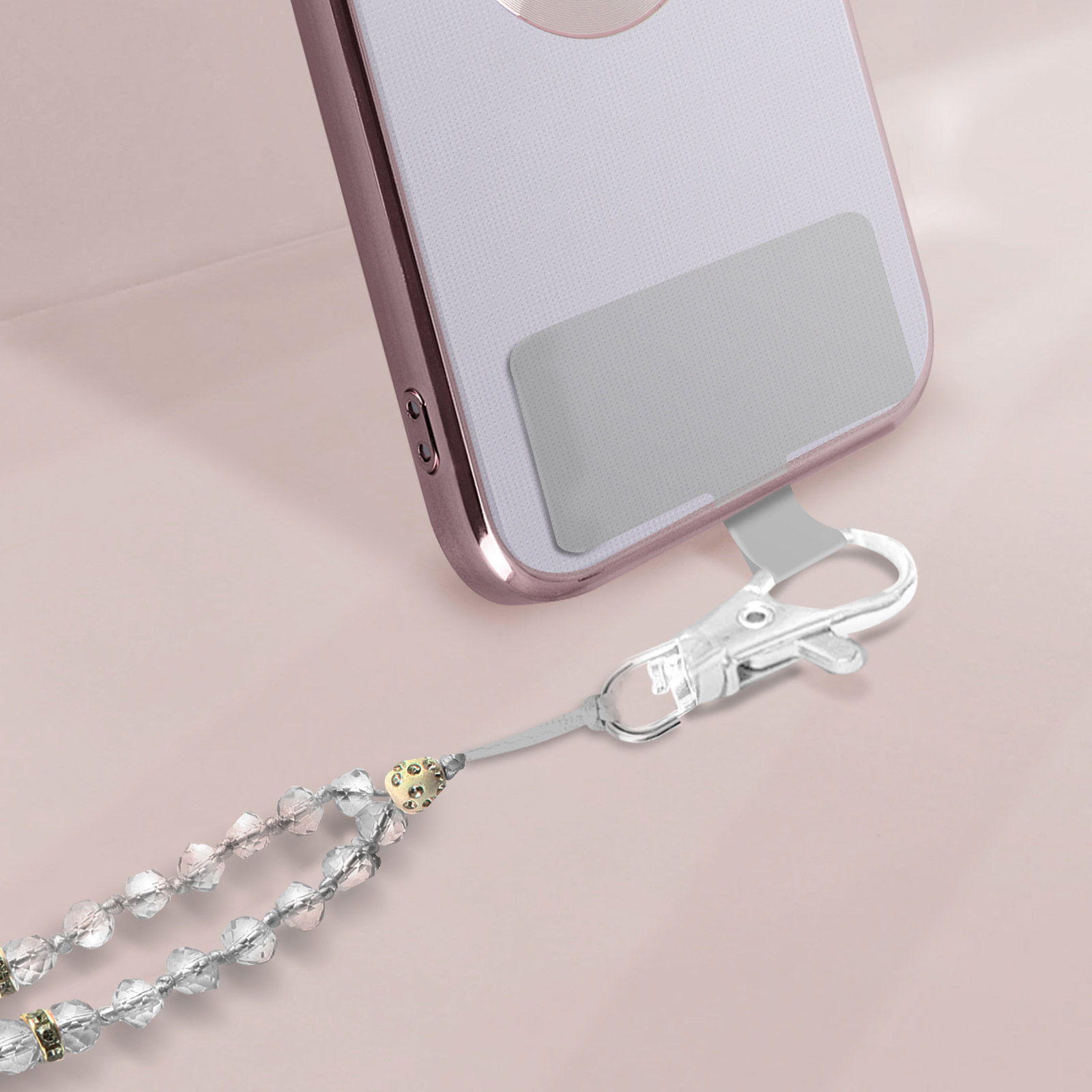Un elegante telefono con cordino di perline e chiusura argentata su sfondo rosa.