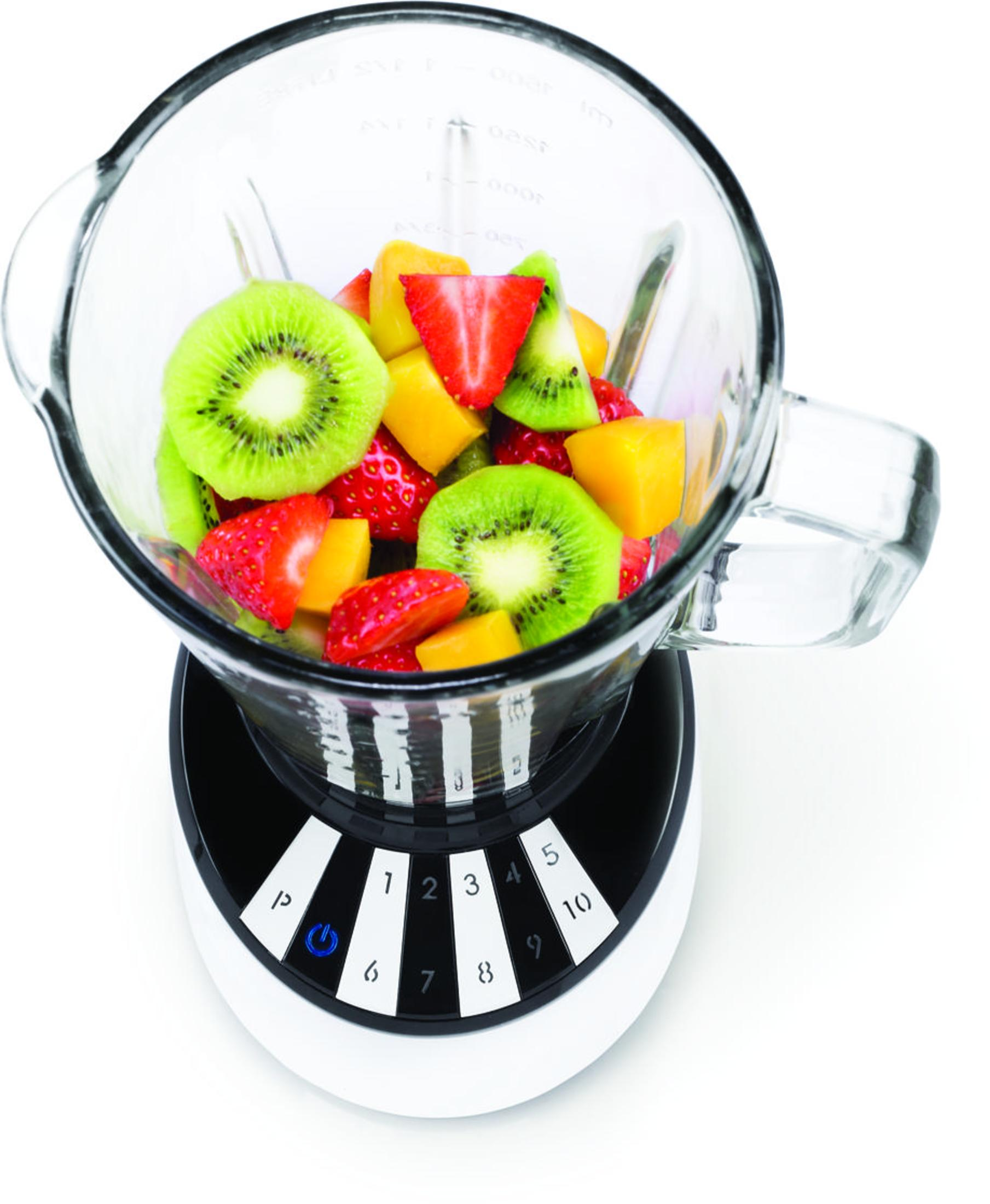 Un boccale per frullatore riempito di fragole, kiwi e pezzi di mango.
