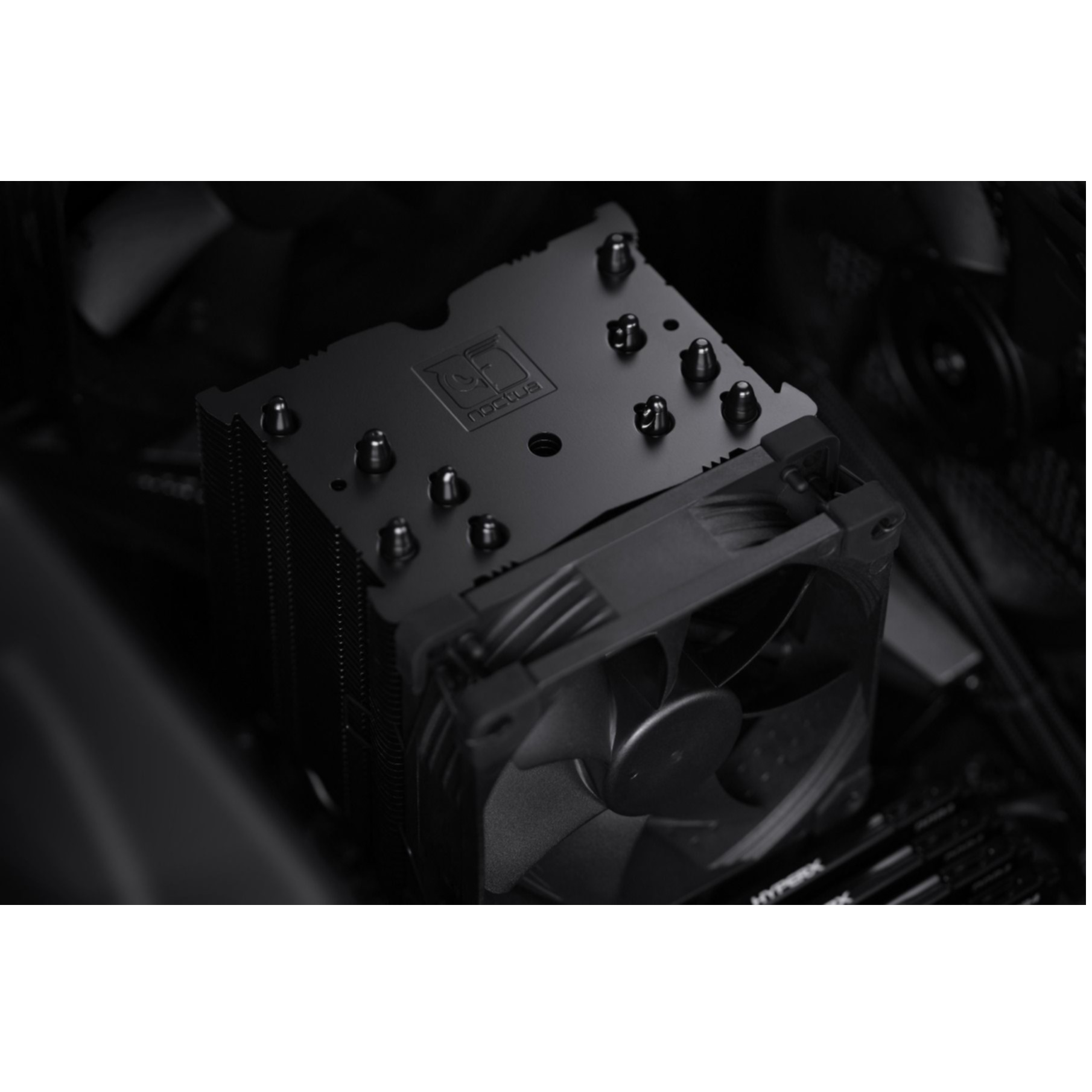 Un dissipatore CPU Noctua nero con ventola è installato in un computer. Sono visibili i moduli RAM.