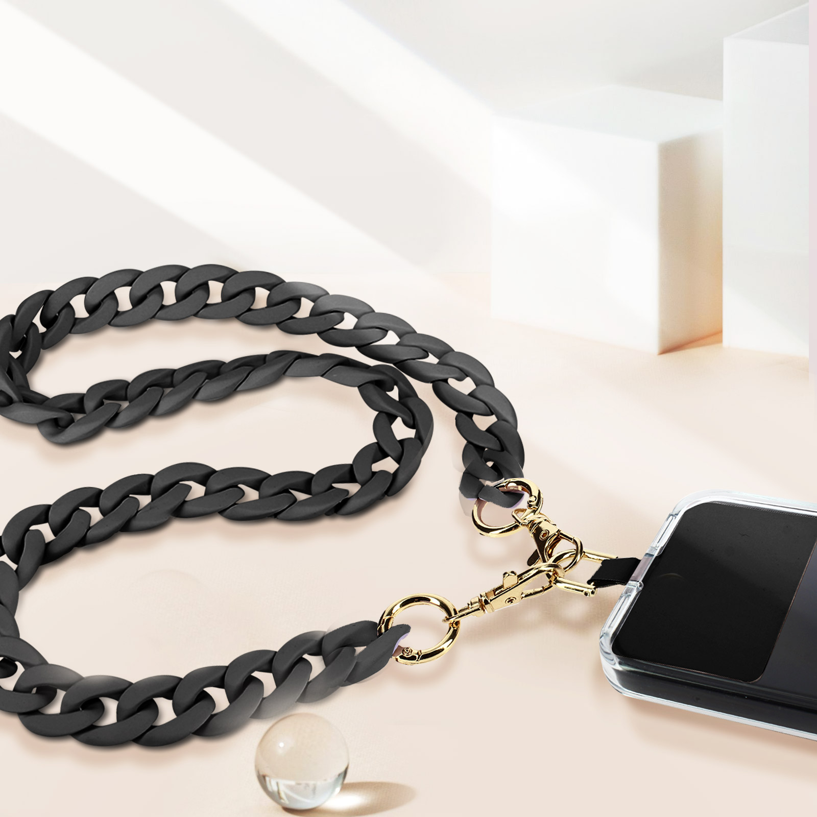 Catena spessa nera con chiusure dorate attaccata a una custodia per telefono.