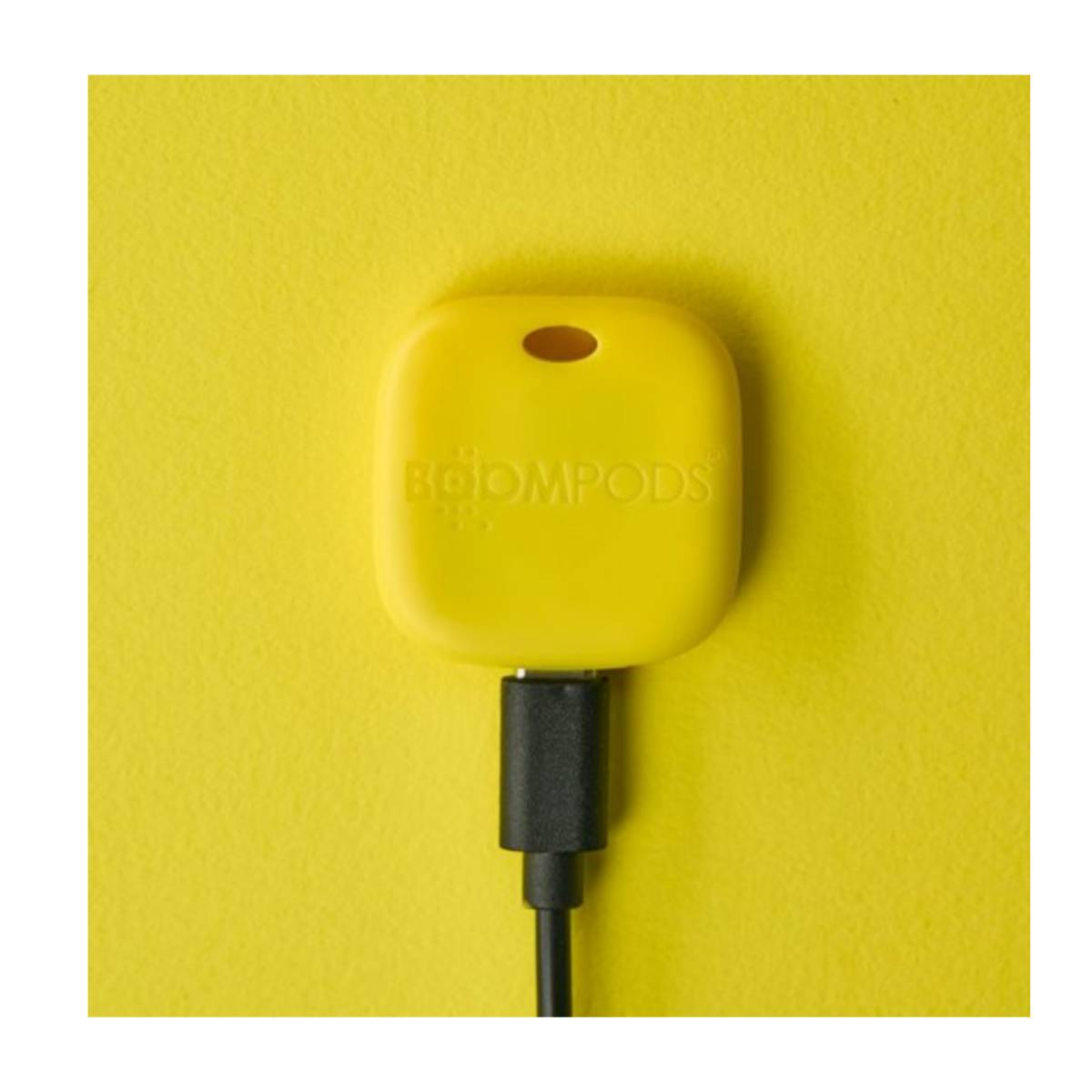 Una custodia di ricarica gialla BOOMPODS con cavo USB nero collegato.