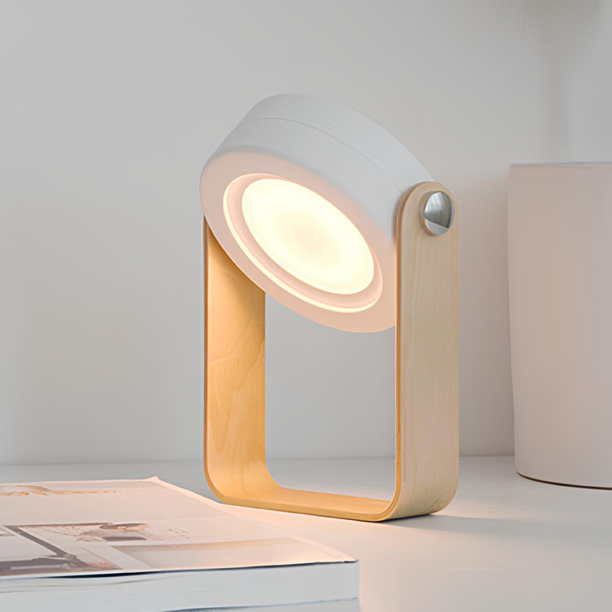 Eine moderne Lampe mit Holzrahmen und weißem Lampenschirm steht auf einem Tisch.