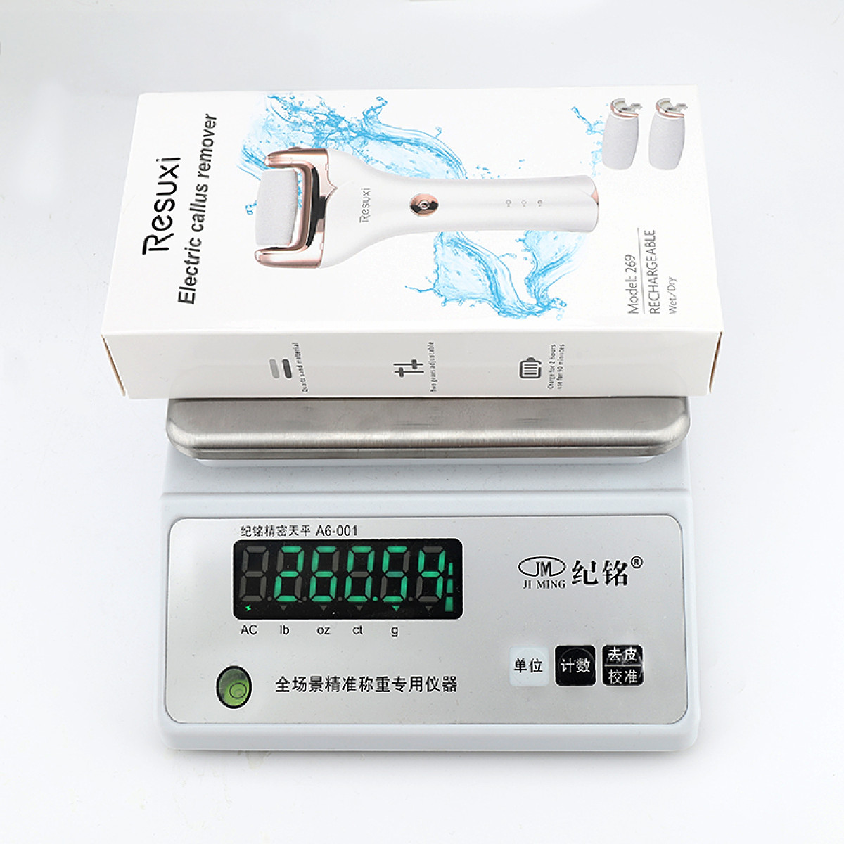 Eine weiße Resuxi-Box für elektrische Hornhautentferner steht auf einer Digitalwaage. Wasserspritzer dargestellt.