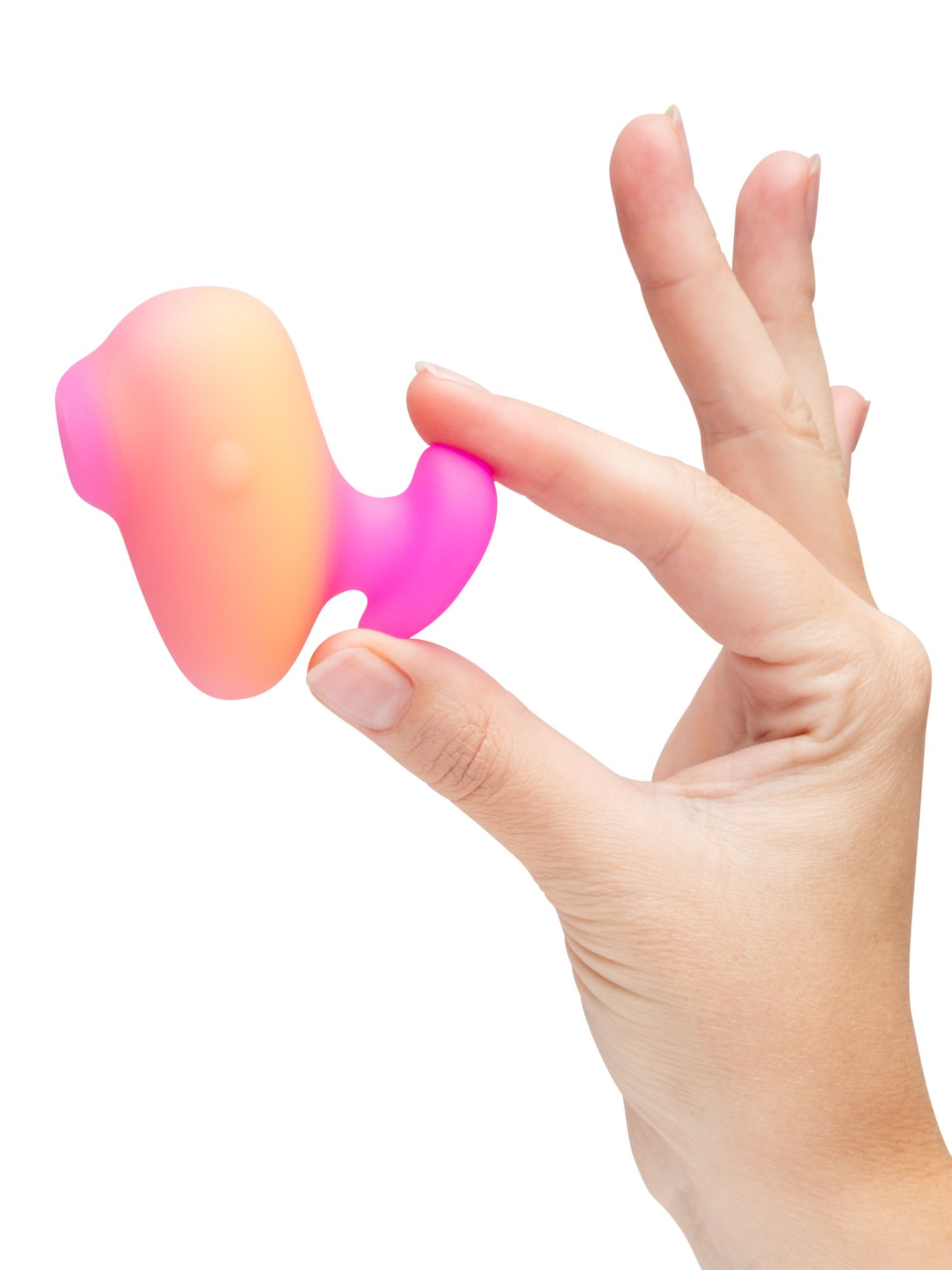Una mano sostiene un juguete de silicona degradado rosa y naranja sobre fondo blanco.