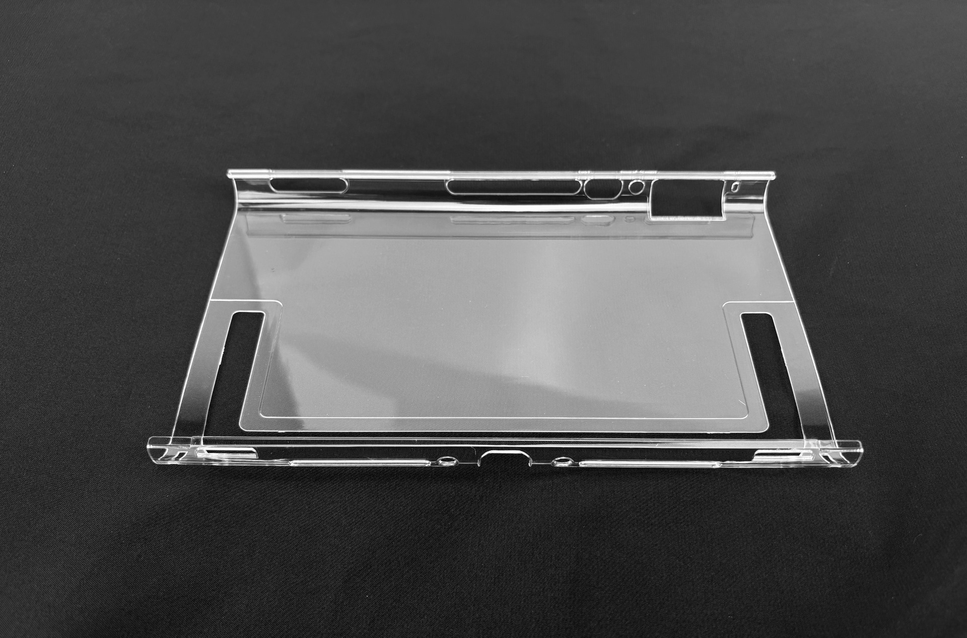 Supporto in plastica trasparente con ritagli per il supporto del dispositivo, su sfondo nero.