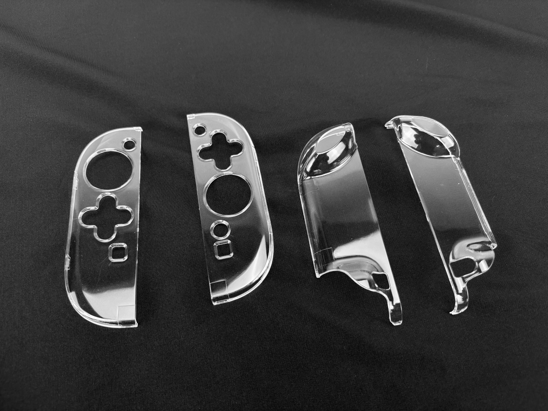 Quattro coperture trasparenti in plastica per Nintendo Switch Joy-Con su sfondo nero.