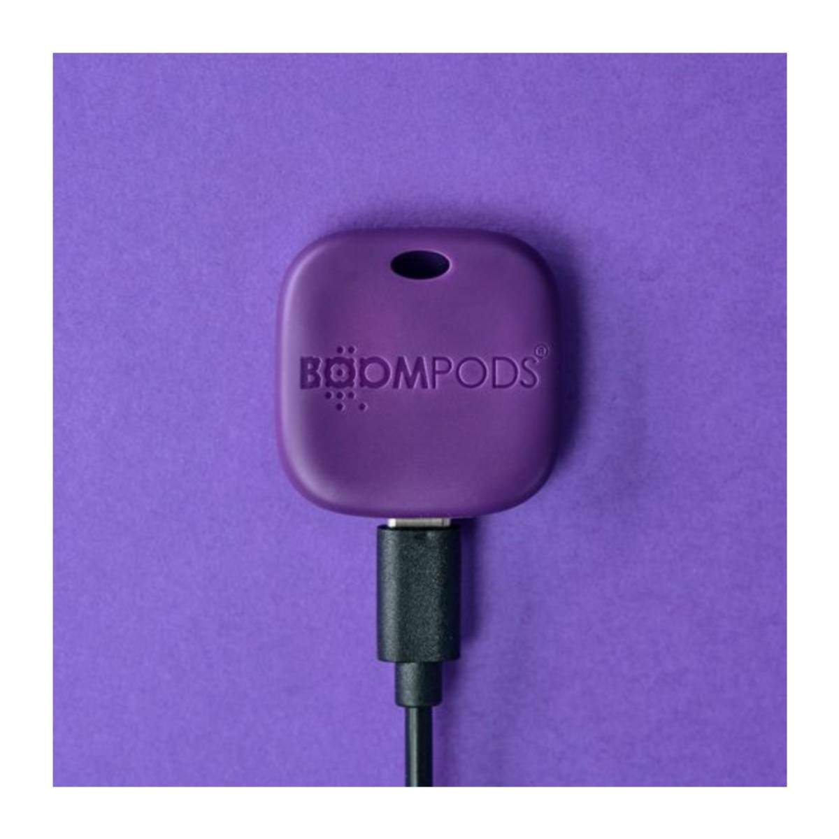 Dispositivo Boompods viola con cavo USB-C collegato, su sfondo viola.