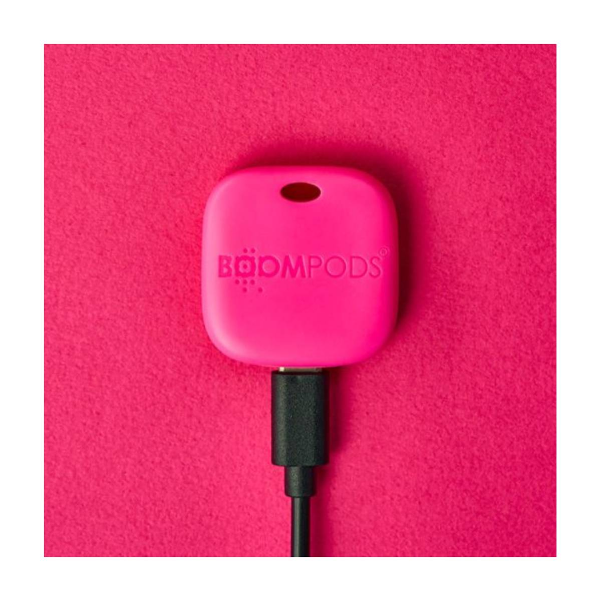 Un tracker Boompods rosa con cavo di ricarica nero su sfondo rosa.