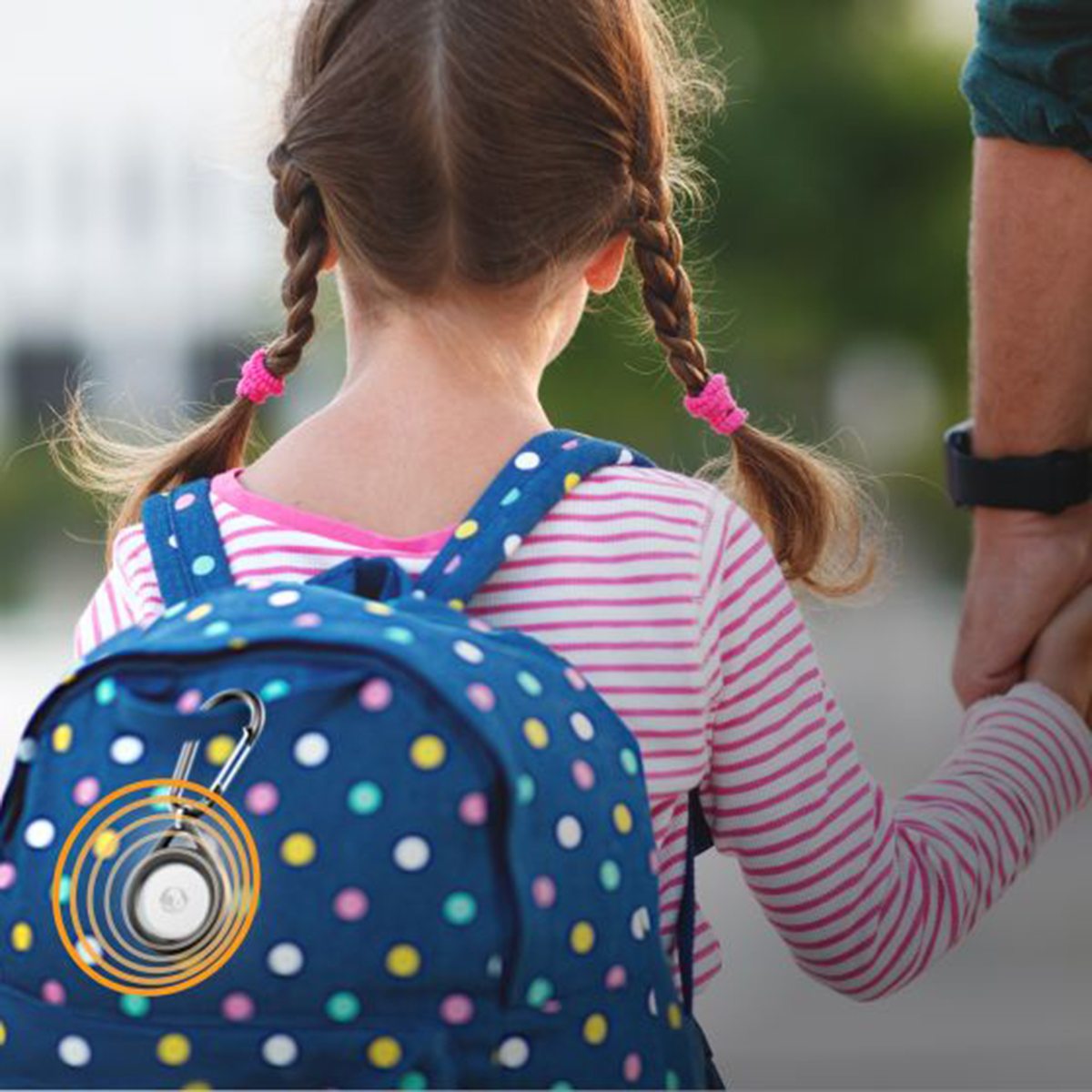Una bambina con le trecce indossa uno zaino blu a pois, tenendo una mano.