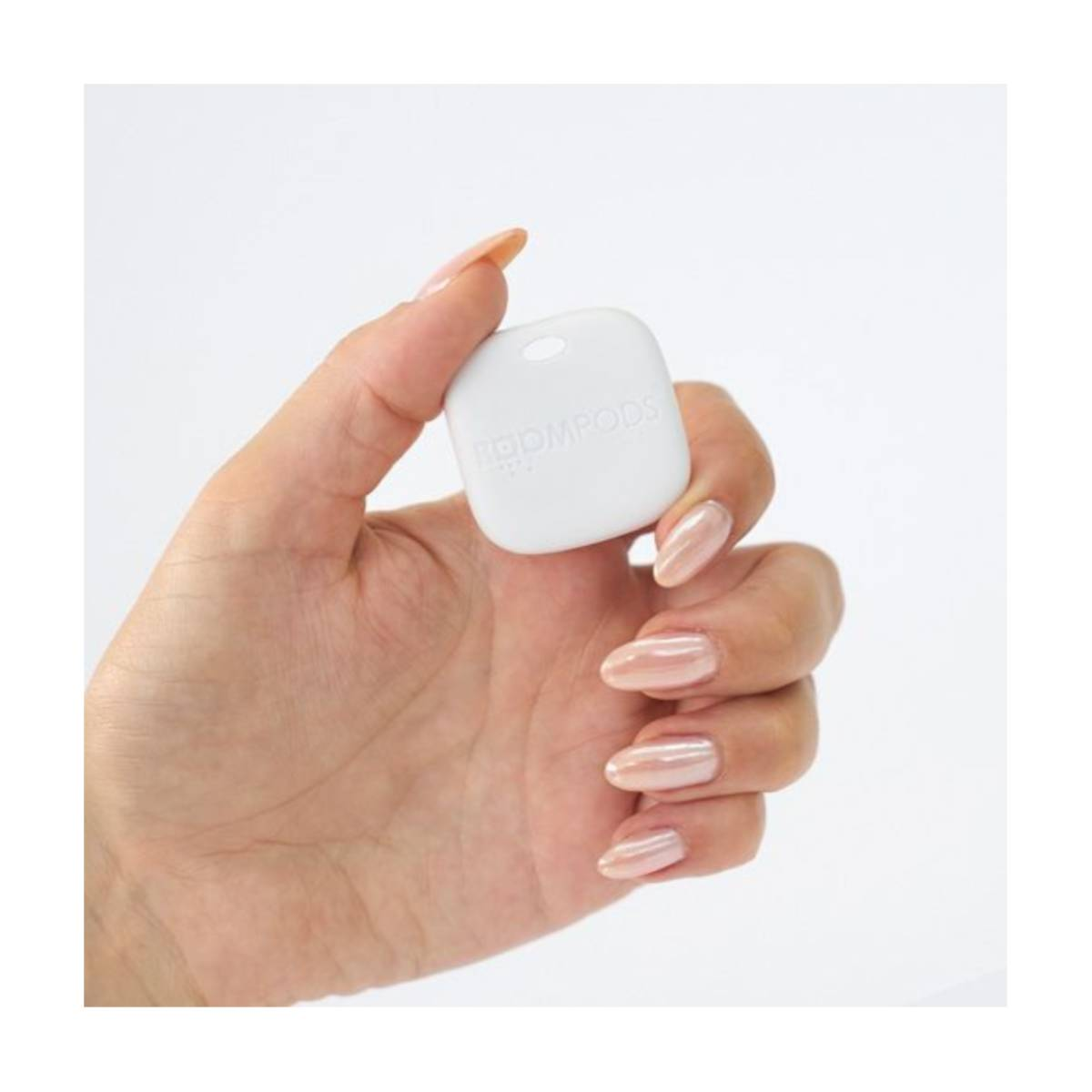 Una mano tiene un dispositivo quadrato bianco con un foro in alto. Il dispositivo ha del testo.