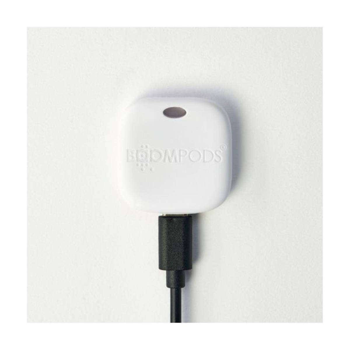 Un dispositivo bianco BOOMPODS con cavo USB-C nero collegato.