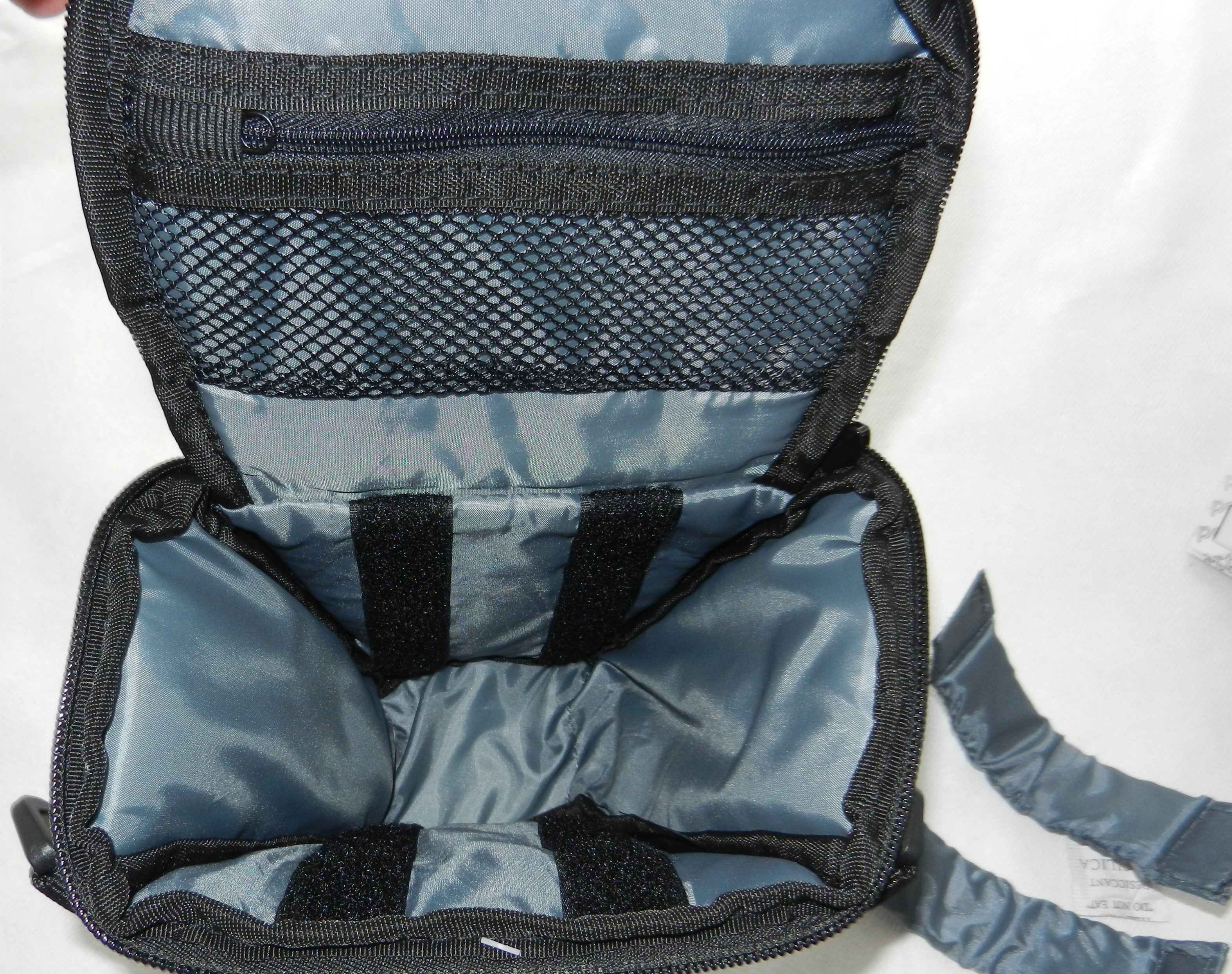 Una borsa fotografica nera aperta con fodera interna blu e cinghie in velcro.