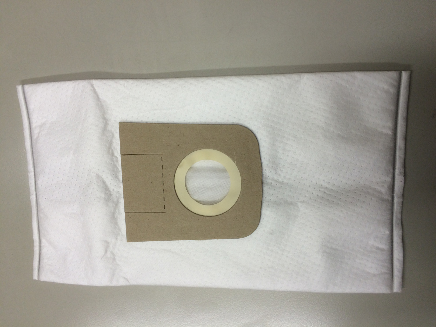 Un sacchetto per aspirapolvere bianco con connettore in cartone marrone e anello rotondo.