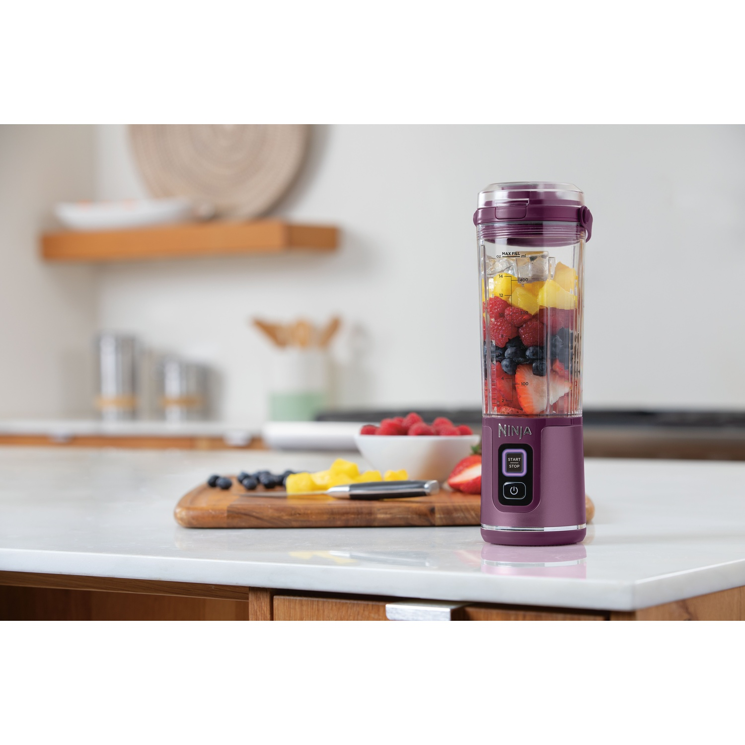 Fioletowy blender Ninja z owocami: truskawki, borówki, maliny i ananas.