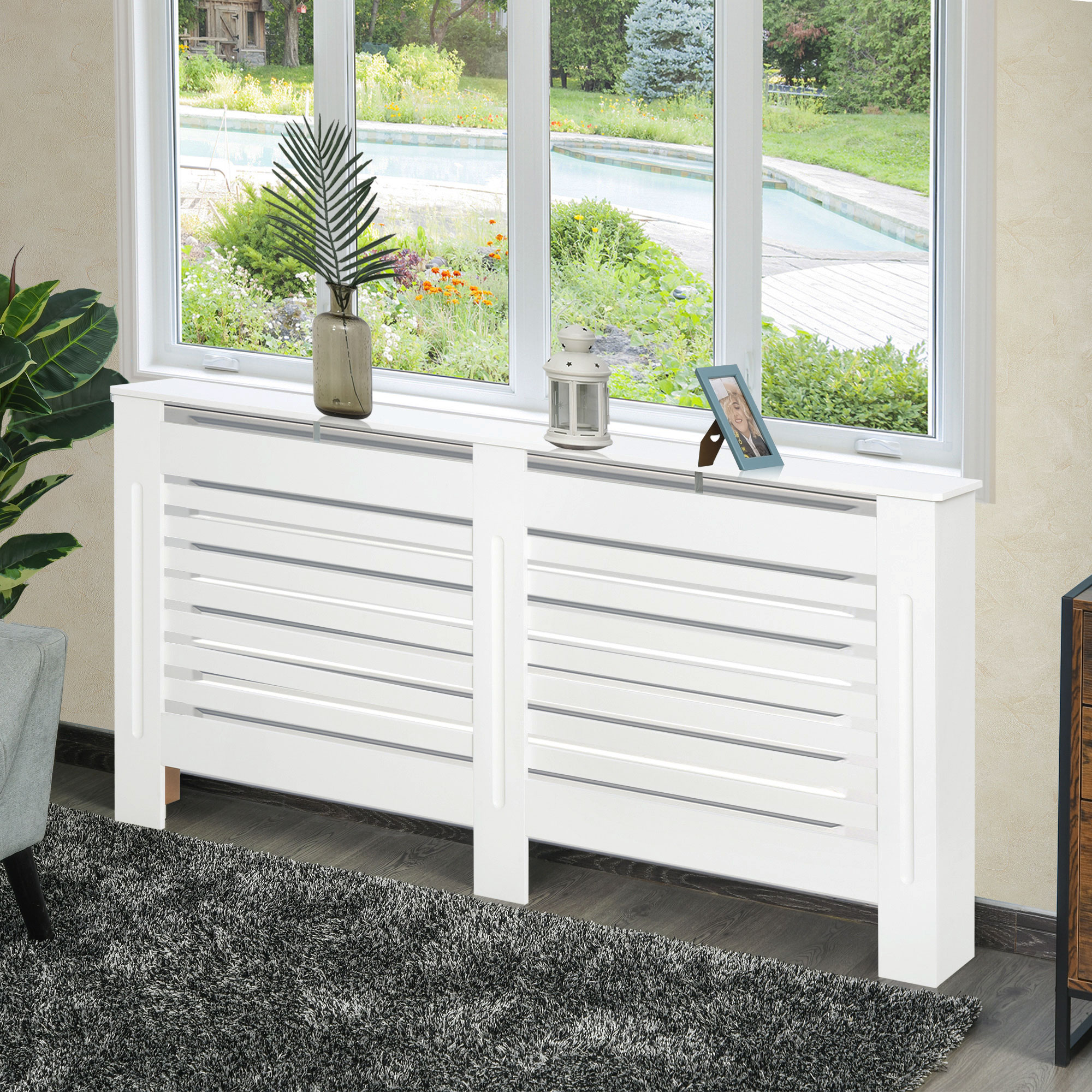 Copritermosifone bianco con anta a persiana, sotto una finestra con vista giardino.