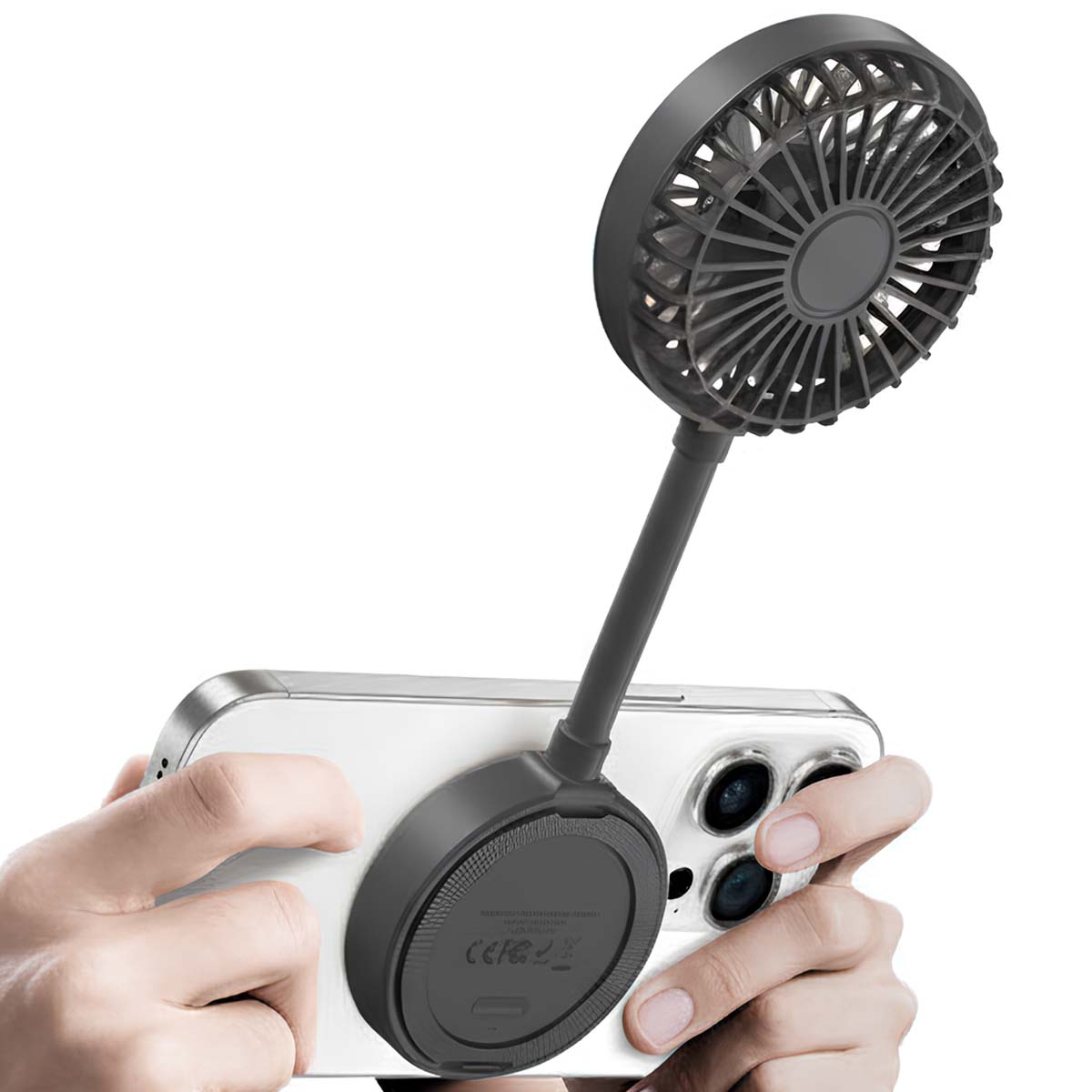 Un mini ventilateur noir est attaché à un smartphone tenu par des mains.
