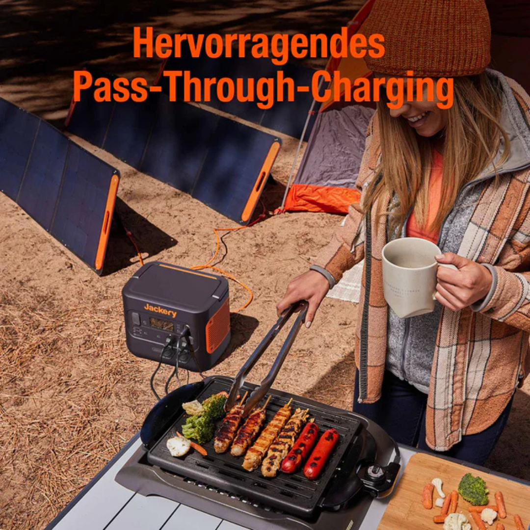 Eine Frau grillt Essen neben einem Zelt mit Solarpanels und einer Powerstation.