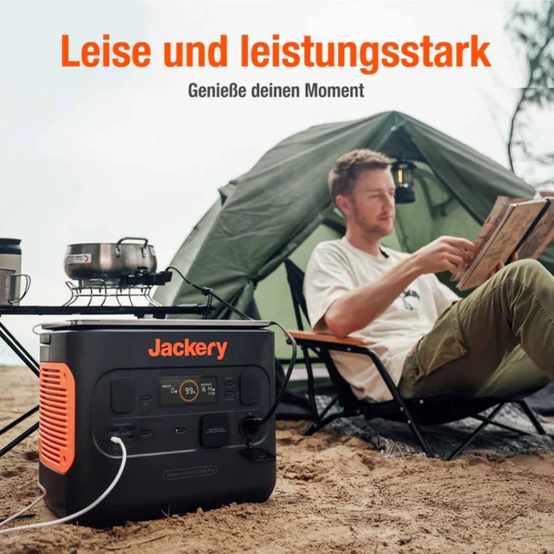 Ein Mann liest in einem Zelt, während ein Jackery-Stromgenerator daneben steht.