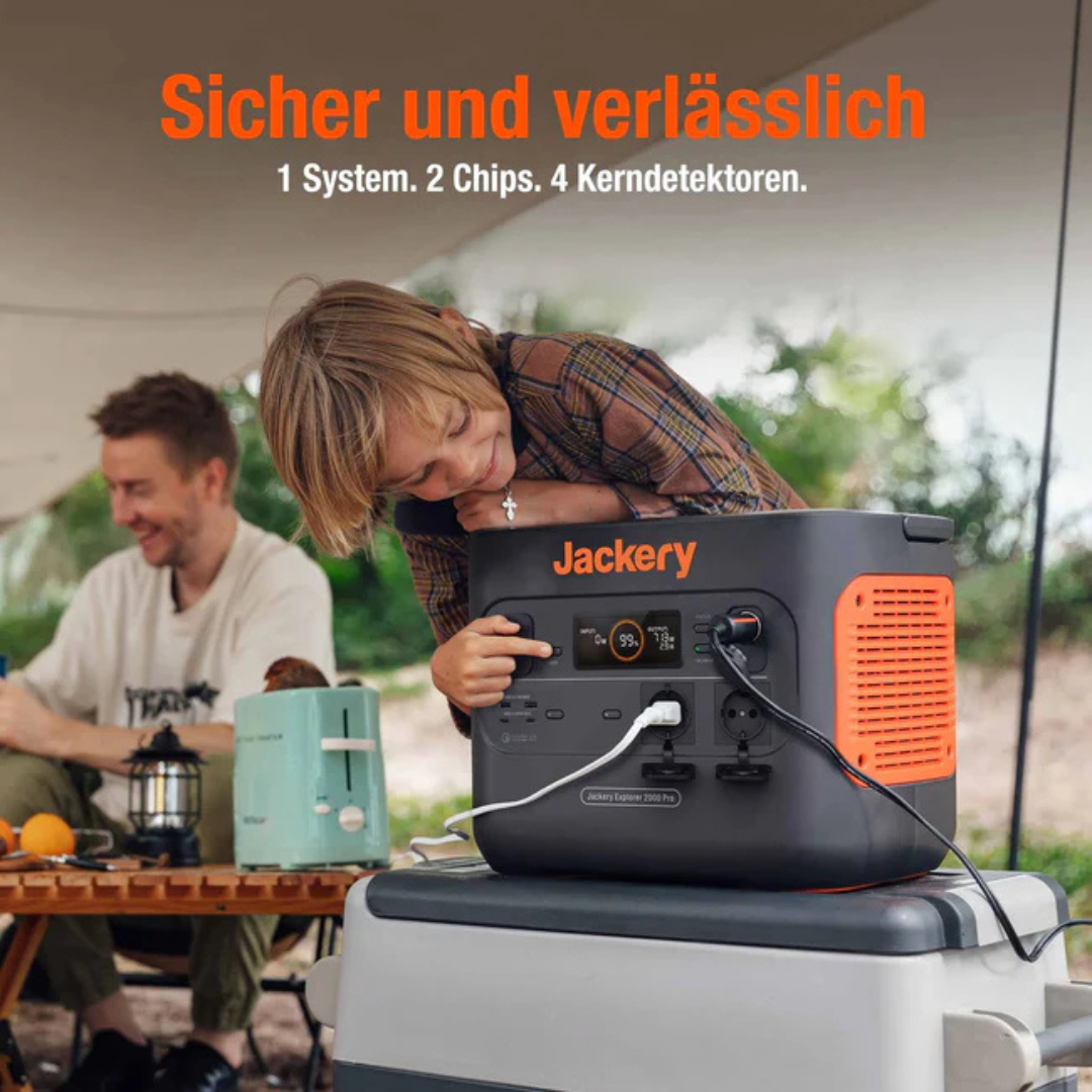 Ein Junge berührt eine Jackery-Powerstation, während ein Mann lächelt. Camping-Setup.