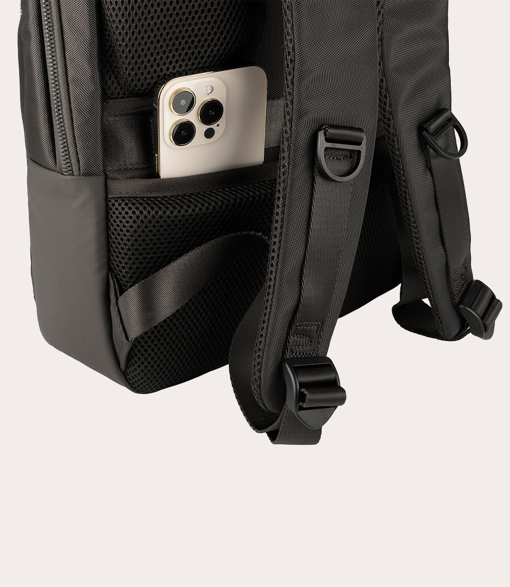 Ein Smartphone befindet sich in der Gesäßtasche eines schwarzen Rucksacks mit gepolsterten Trägern.