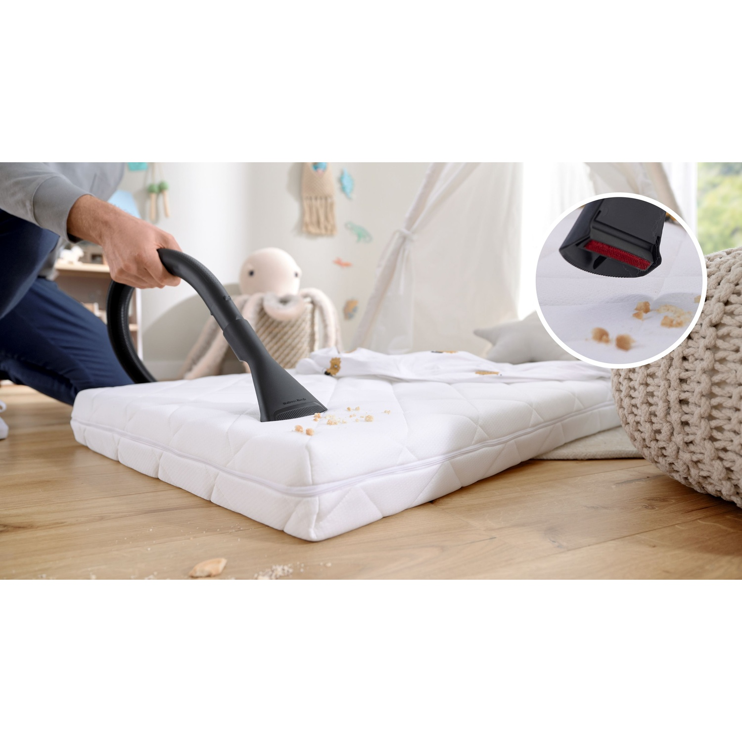 Osoba odkurza biały materac odkurzaczem ręcznym.