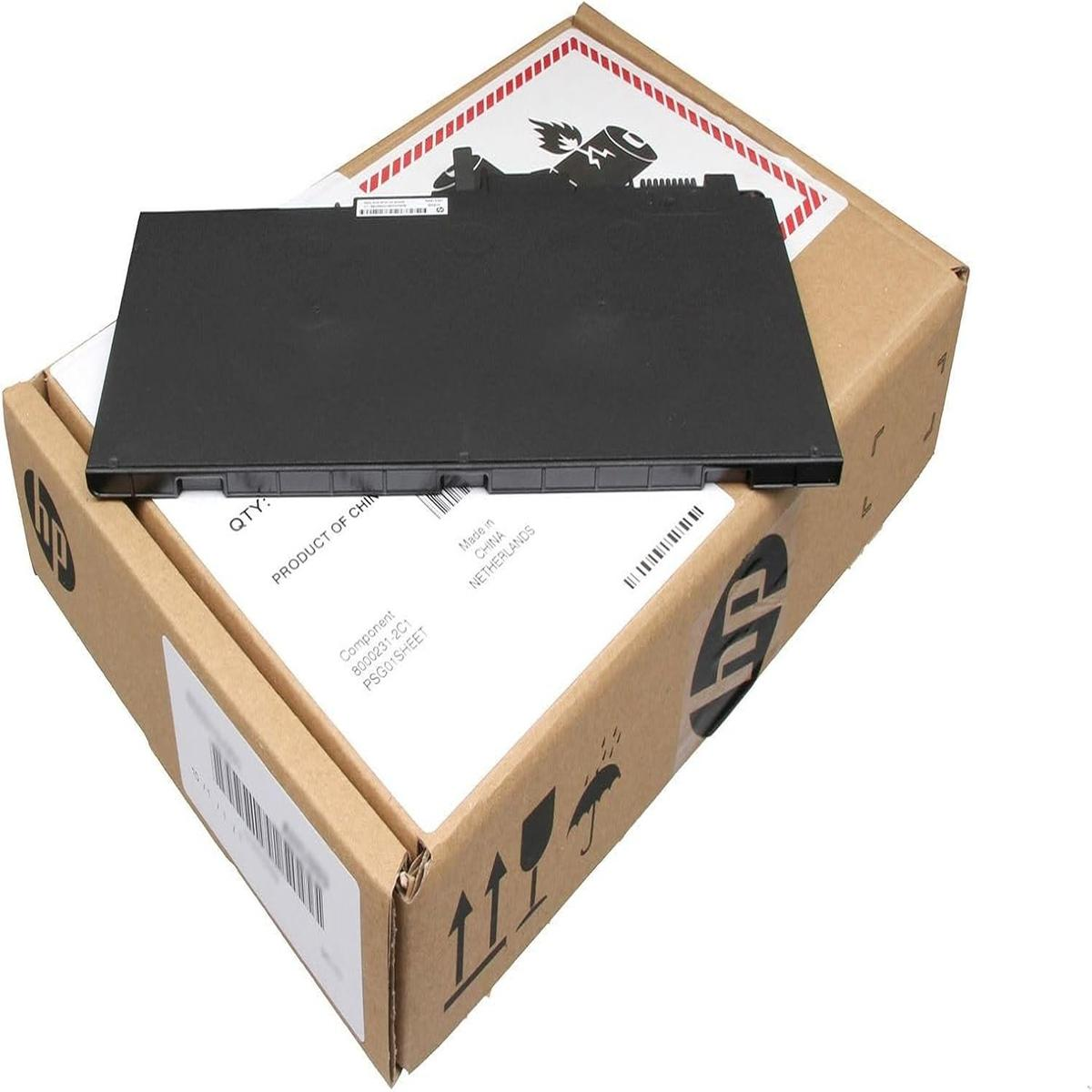 Una batteria nera per laptop poggia su una scatola di cartone aperta con marchio HP ed etichette di spedizione.