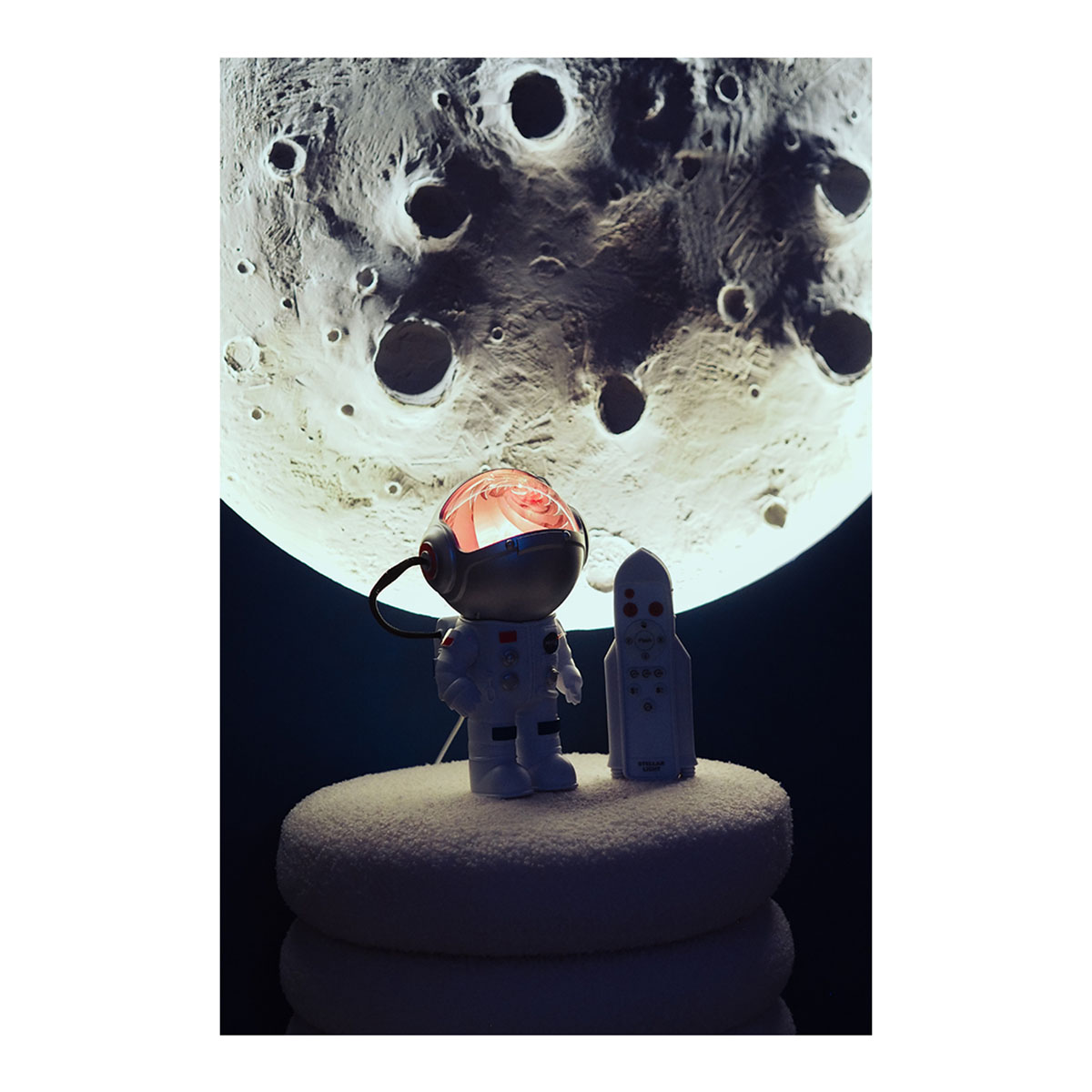 Figura di astronauta e razzo su cuscino bianco con sfondo lunare.