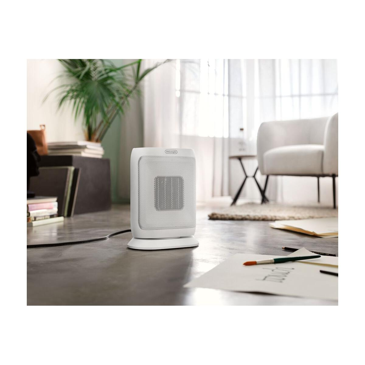 Un termoventilatore bianco su pavimento in cemento. Una poltrona sullo sfondo.