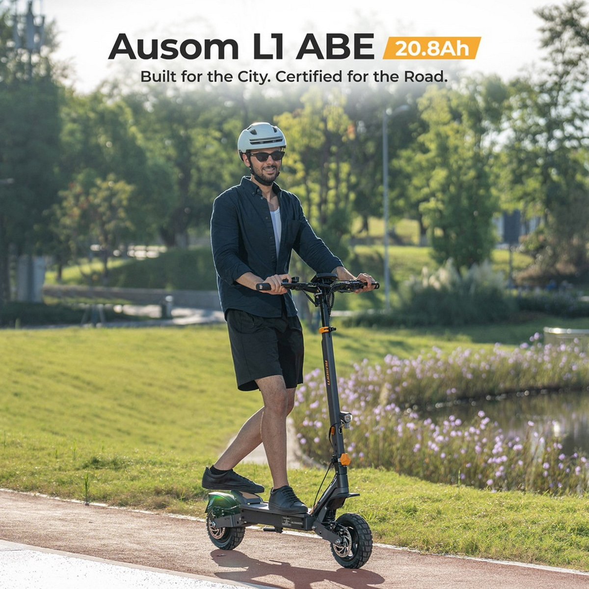 Uomo con casco guida monopattino elettrico nero su sentiero, all'aperto con alberi e acqua.