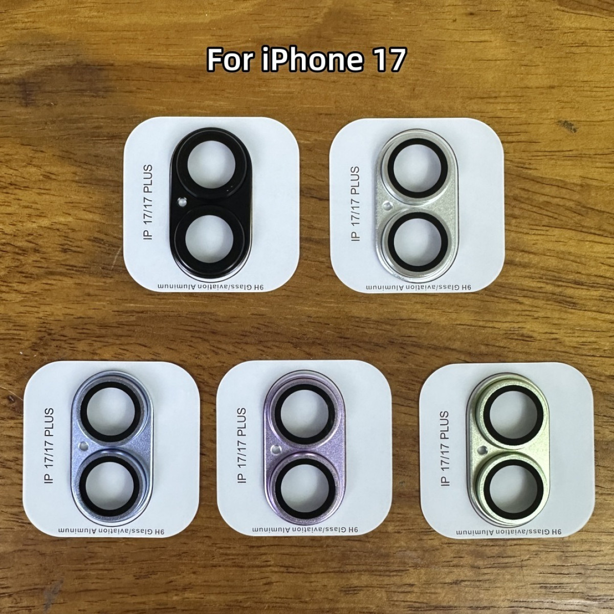 Cinque copriobiettivo per fotocamera iPhone 17/17 Plus nei colori nero, argento, blu, viola, verde.