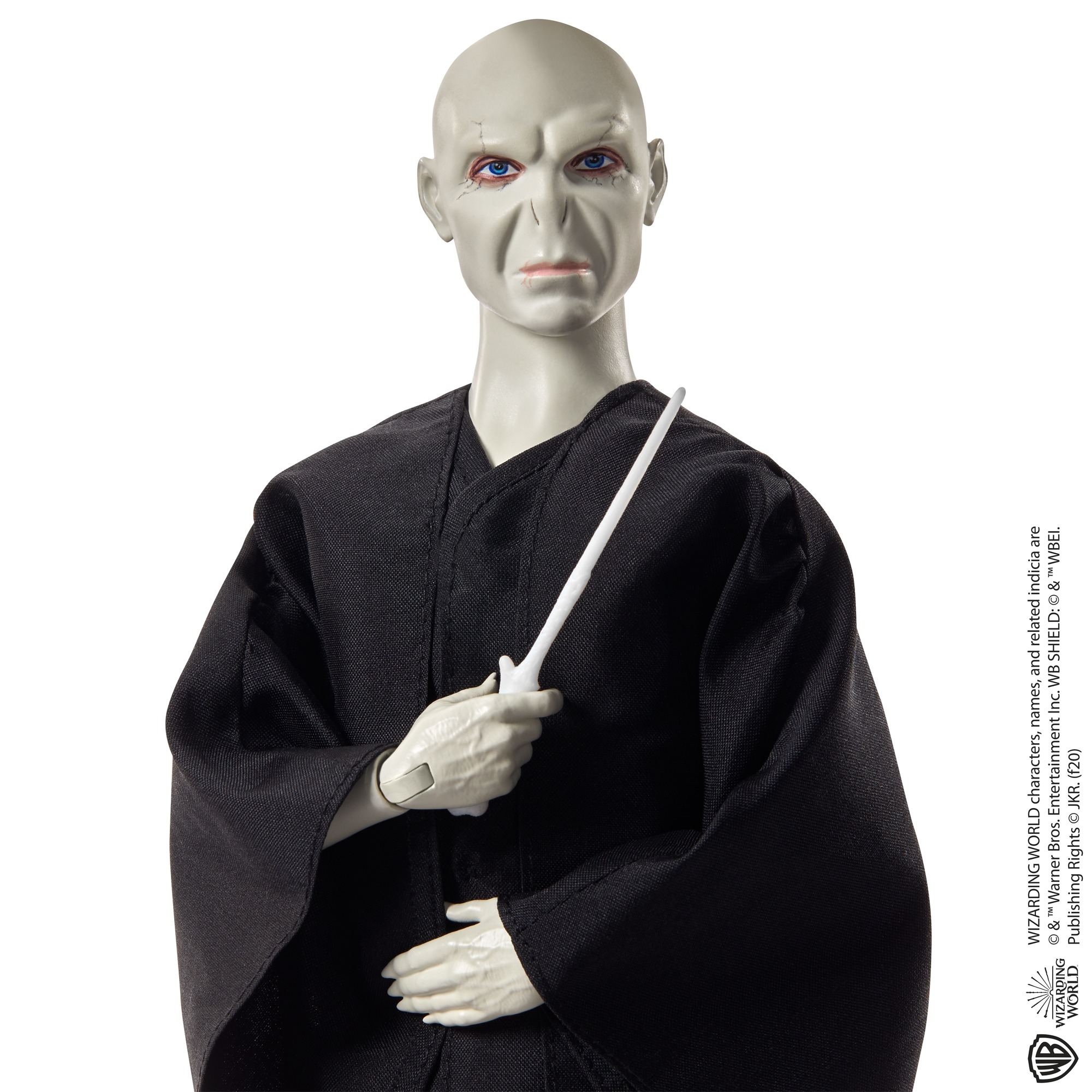 Una bambola di Voldemort in vesti nere tiene una bacchetta bianca su sfondo bianco.