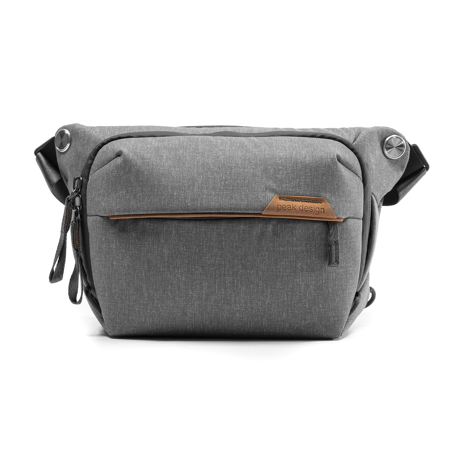 Un sac bandoulière Peak Design gris avec accent cuir marron et quincaillerie argentée, fond blanc.
