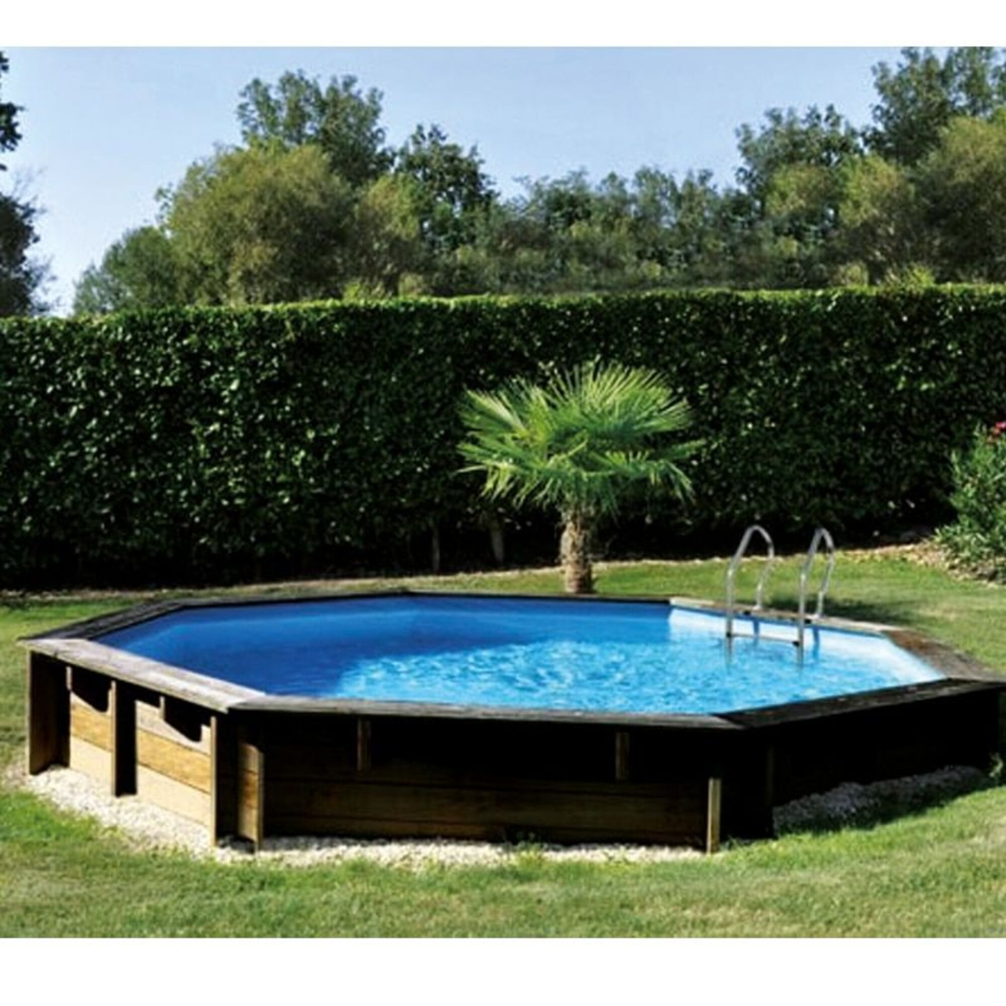 Piscina octogonal de madera con agua azul y escalera metálica. Rodeada de césped verde y árboles.