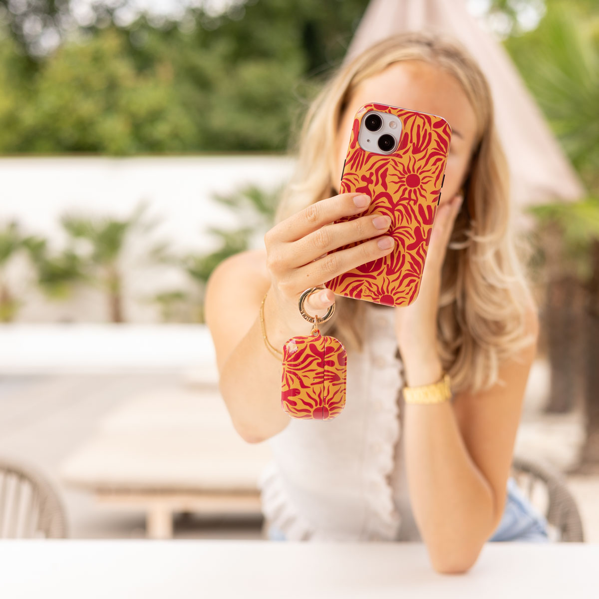 Una donna si scatta un selfie con un telefono in una custodia con motivo solare.