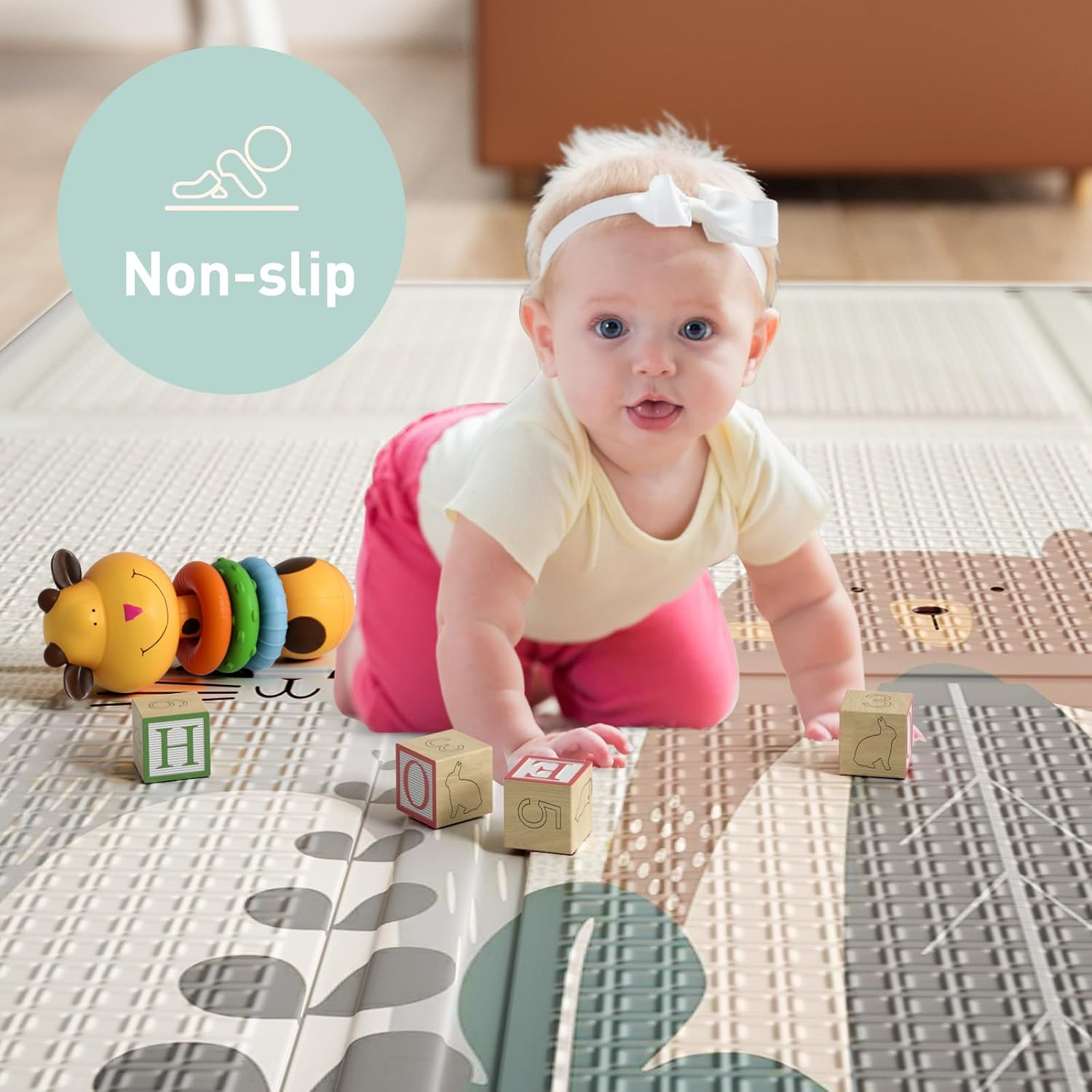 Baby auf Händen und Knien auf einer Spielmatte mit Spielzeug. Rutschfeste Text auf Matte.