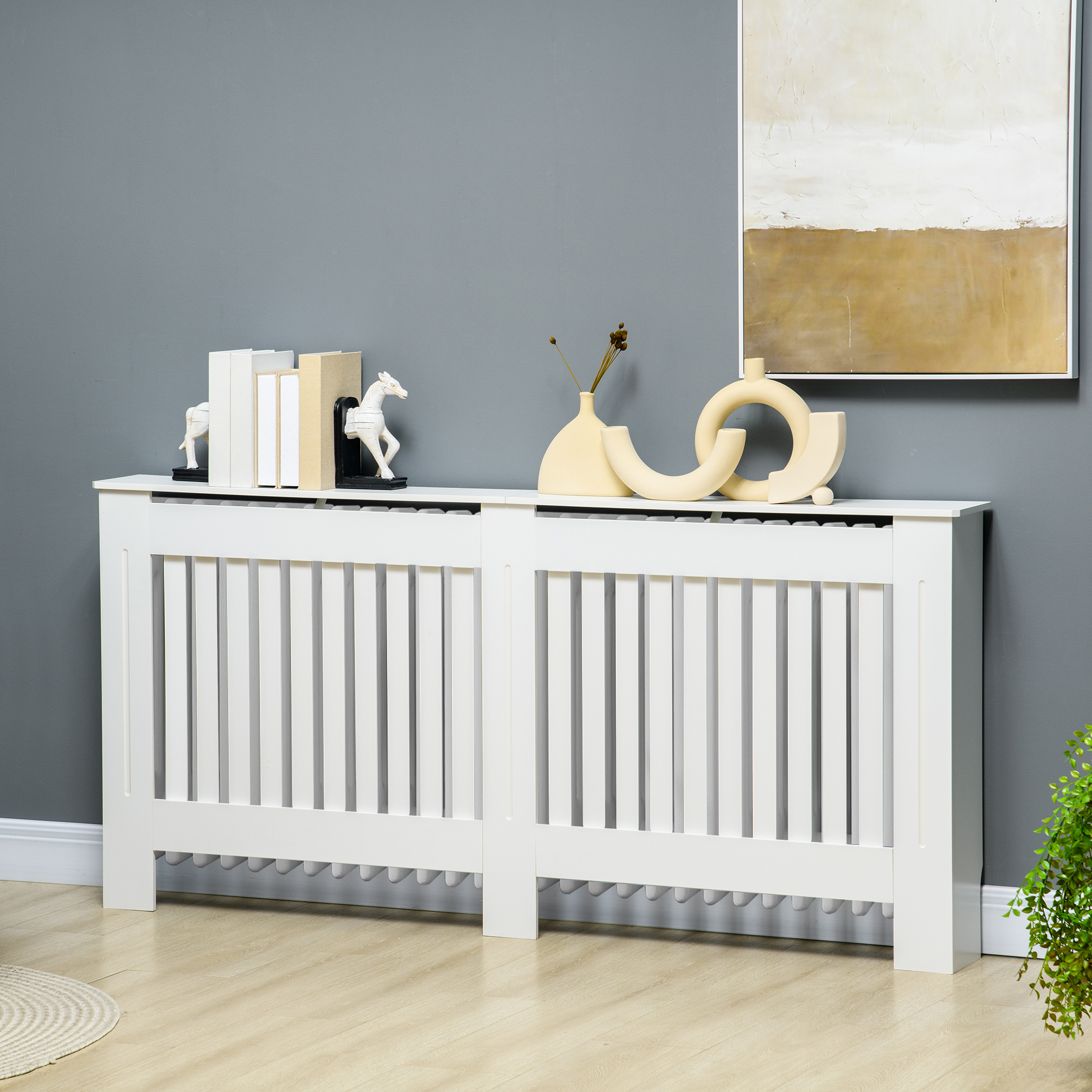 Copritermosifone bianco con doghe verticali, su pavimento in legno. Decorato con libri, statue di cavalli e vasi.
