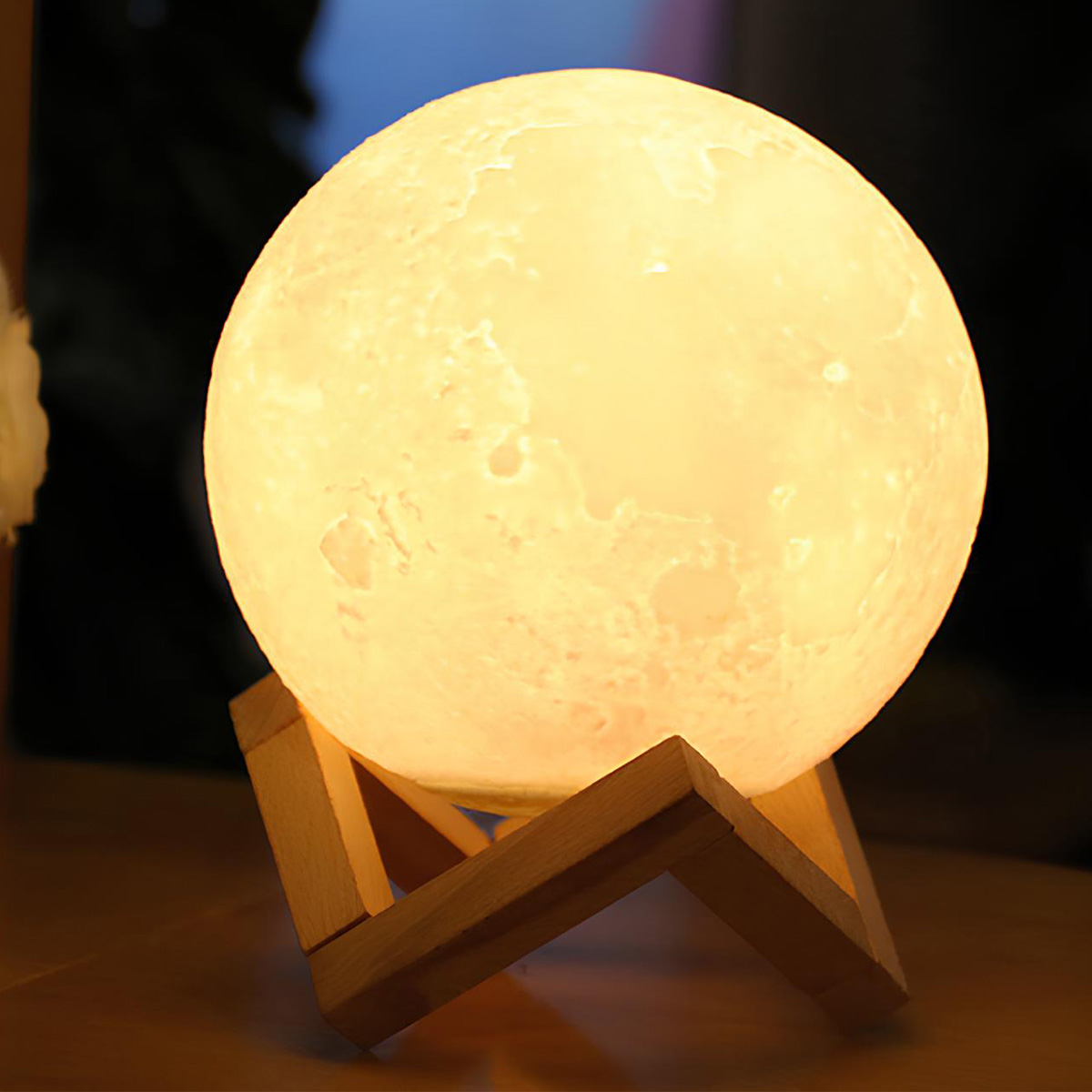 Eine leuchtende Mondlampe steht auf einem Holzständer und wirft ein warmes gelbes Licht.