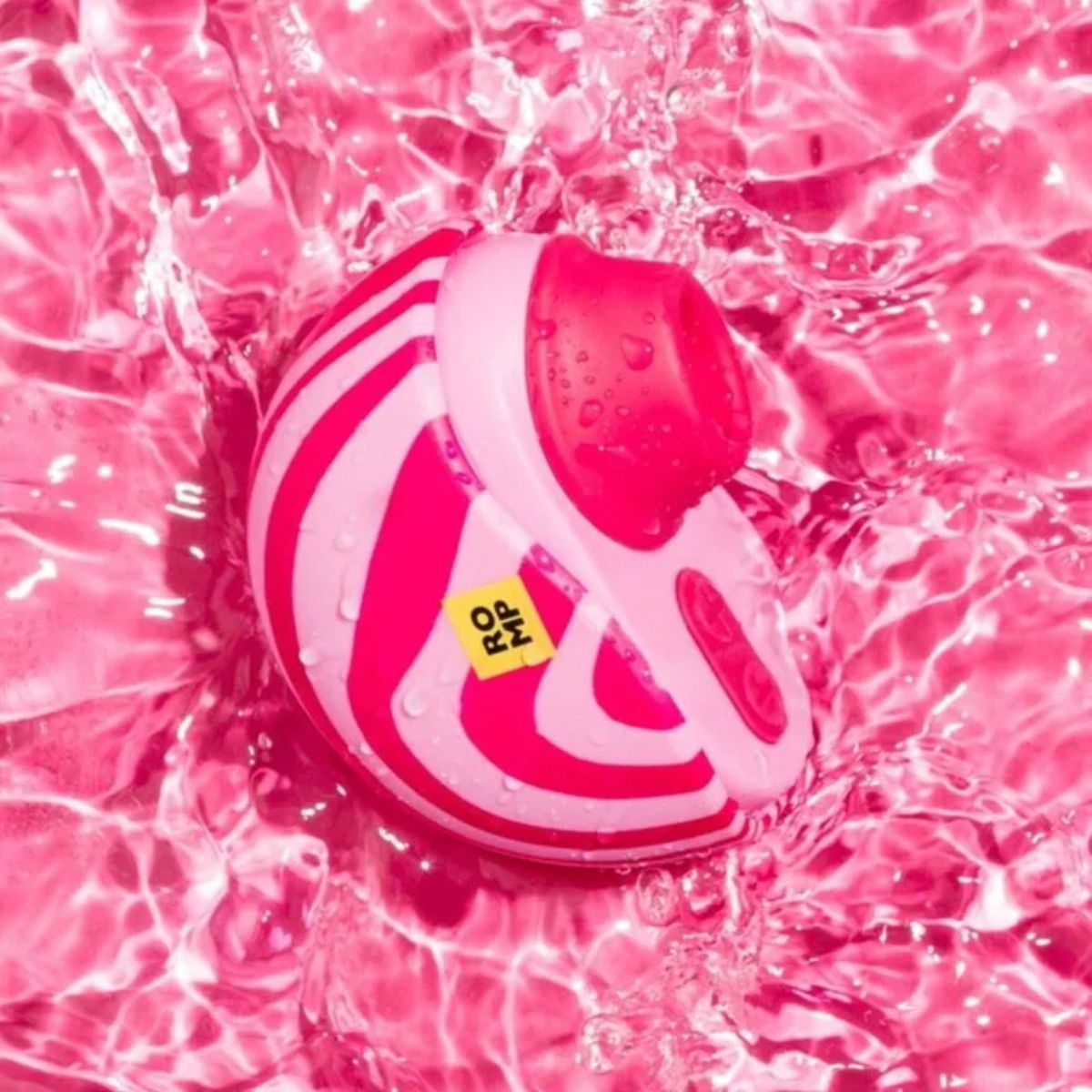 Un juguete de rayas rosas y blancas sumergido en agua rosa con ondas.