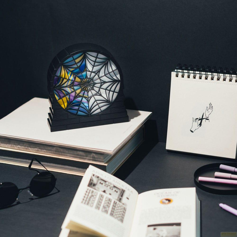 Un objeto con diseño de telaraña y cristal de colores se apoya en libros junto a un cuaderno.