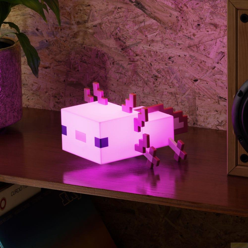 Różowa lampa axolotl z Minecrafta stoi na drewnianej półce z rośliną i głośnikiem.