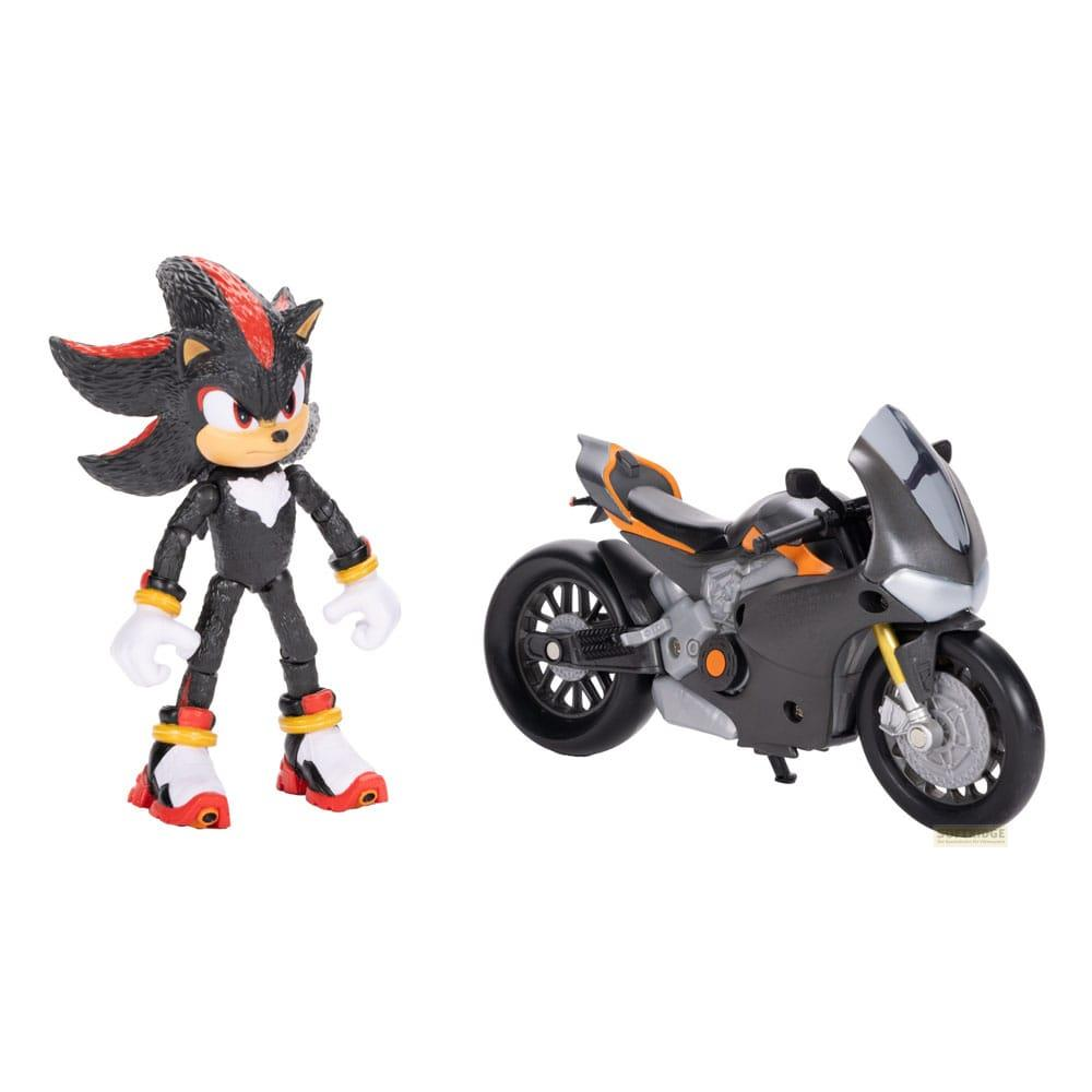 La figura de Shadow the Hedgehog está a la izquierda de una motocicleta negra y naranja sobre fondo blanco.