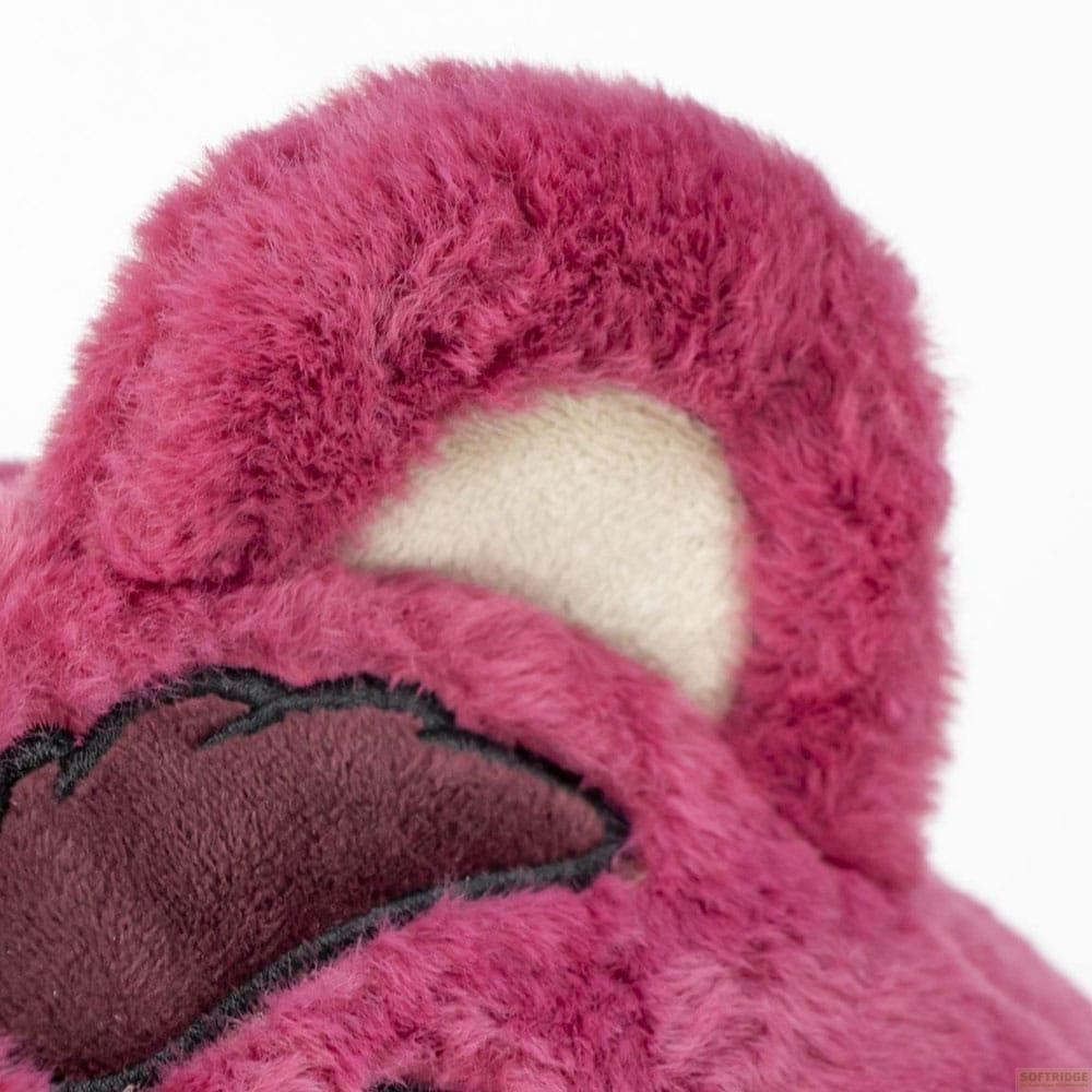 Primer plano de la cabeza de un oso rosa y peludo con oreja beige y detalles bordados negros.