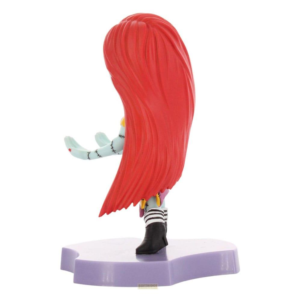 Una muñeca con pelo rojo y manos azules está sobre una base morada.
