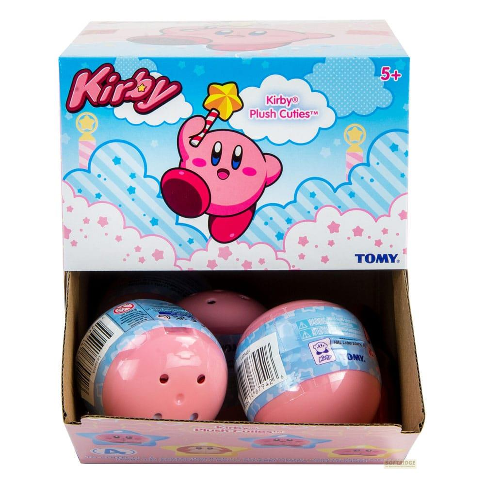 Une boîte ouverte montre trois peluches Kirby roses et sphériques.