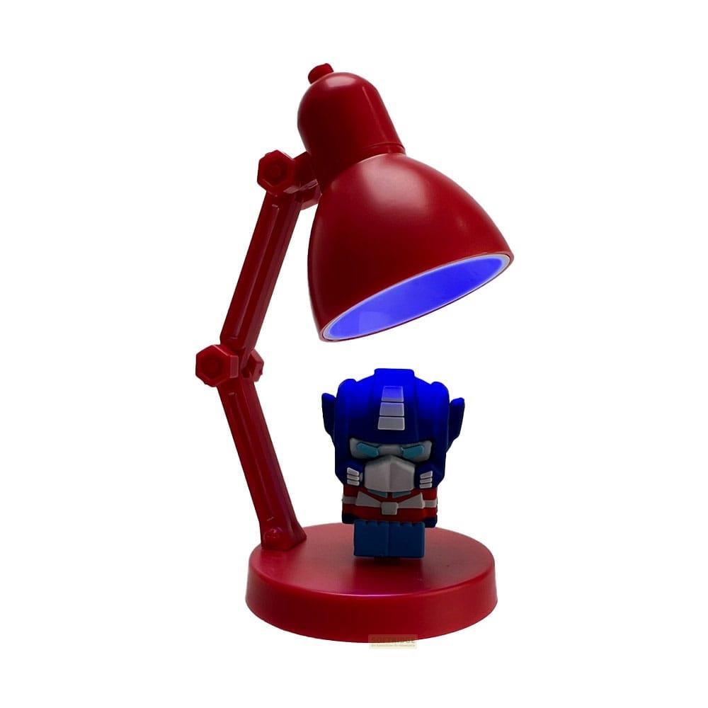 Eine rote Schreibtischlampe wirft blauen Schein auf eine kleine Optimus Prime Figur.