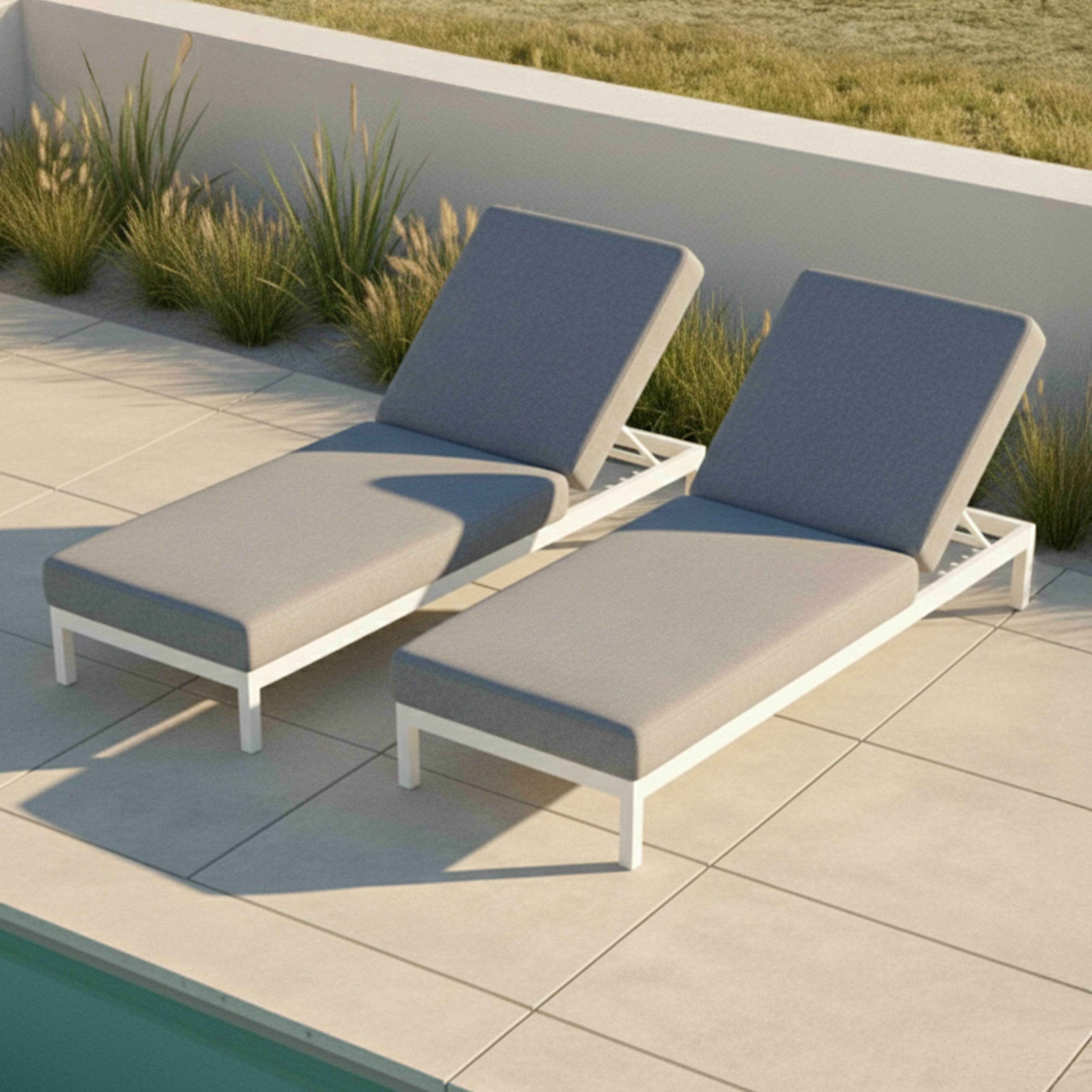 Zwei graue Liegestühle mit weißem Rahmen stehen auf einer gefliesten Terrasse neben einem Pool.